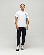 Mens Crazy Bunny Graphic Tee, a classic fit white jersey t-shirt featuring a small, vibrant orange, yellow, and black stylized Psycho Bunny graphic print on the left chest.
