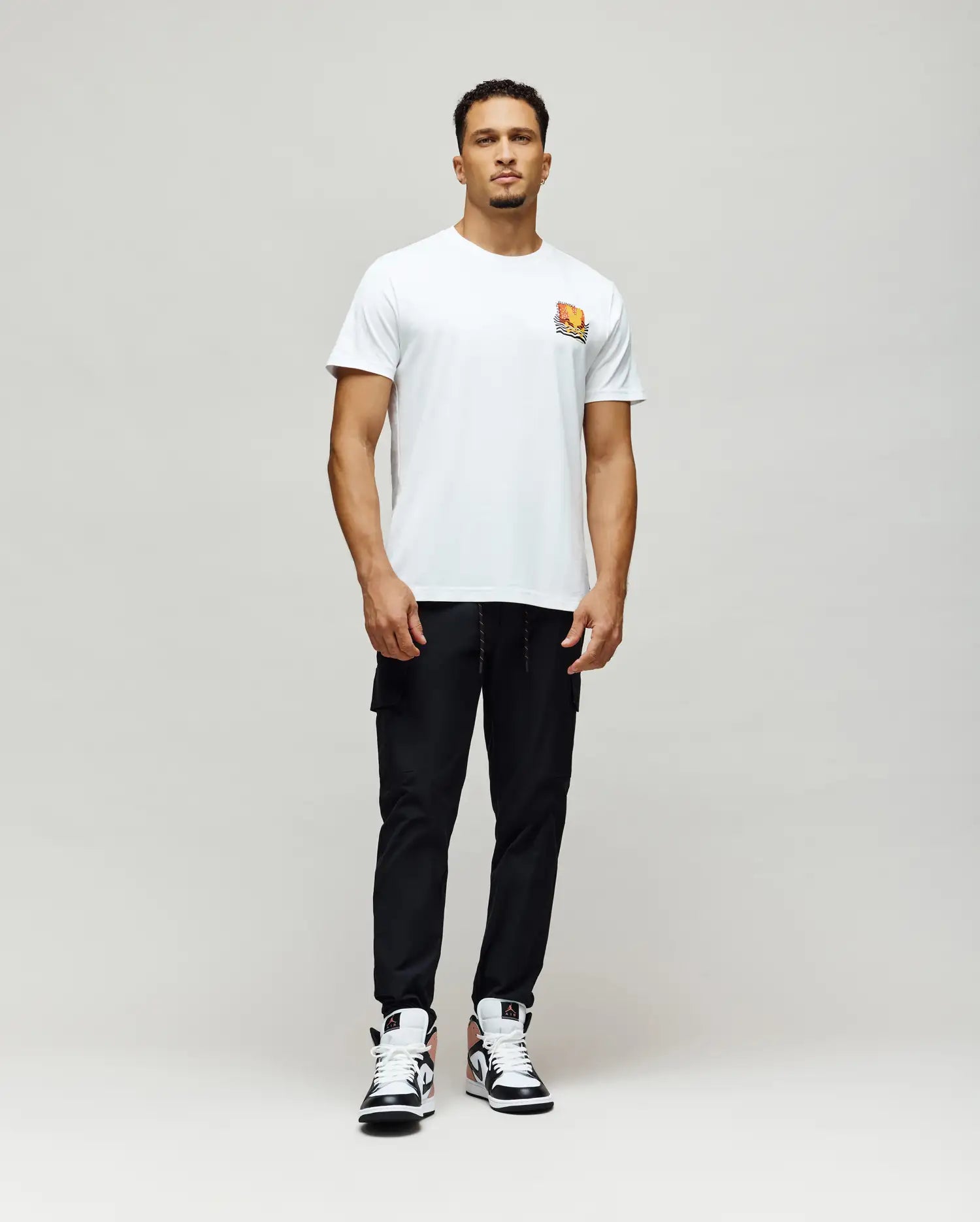 Mens Crazy Bunny Graphic Tee, a classic fit white jersey t-shirt featuring a small, vibrant orange, yellow, and black stylized Psycho Bunny graphic print on the left chest.