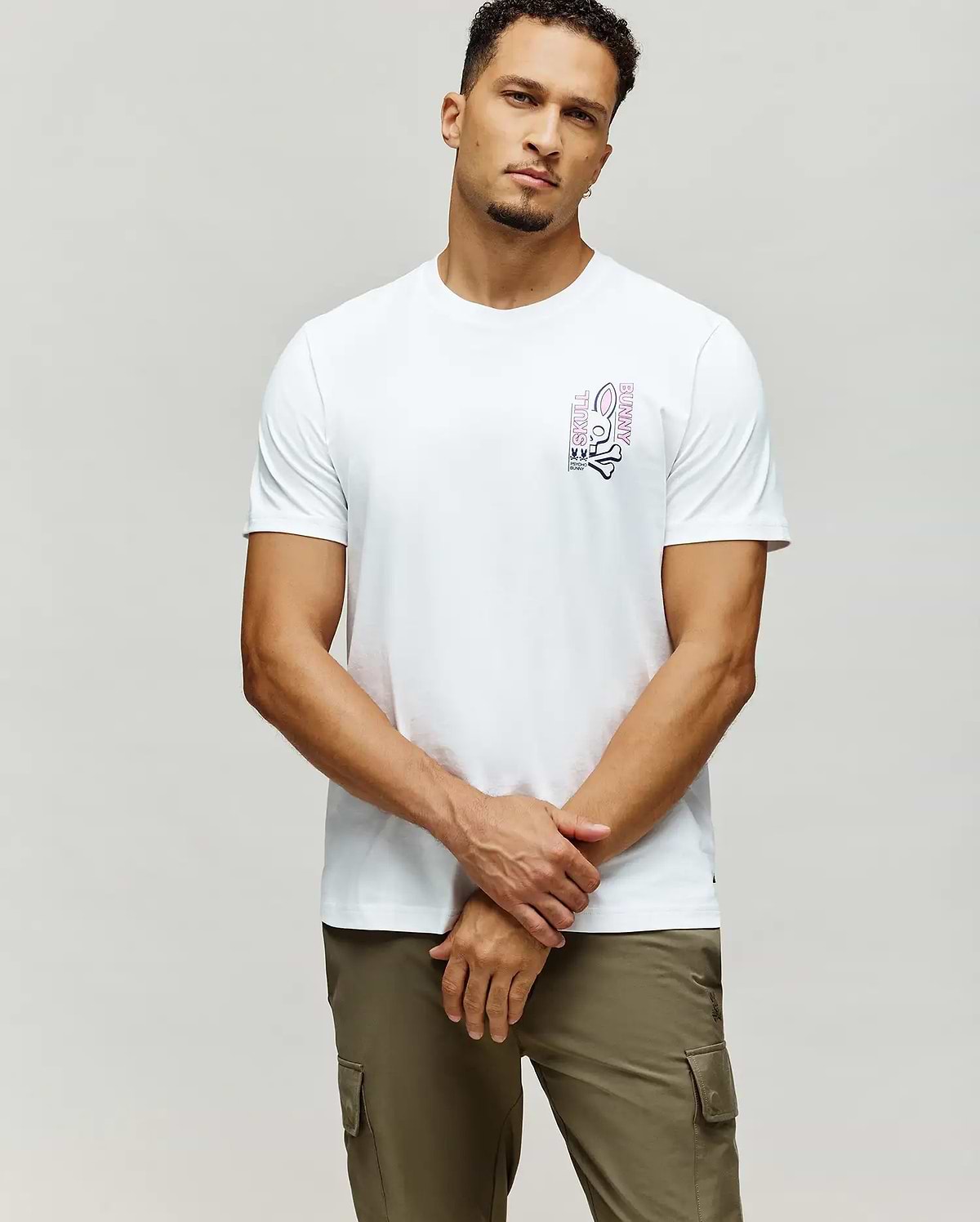White Mens Skull Bunny Graphic Tee, classic fit, soft jersey fabric, with a vibrant pink and black vertical Skull Bunny graphic on the left chest, featuring the iconic logo and text.
