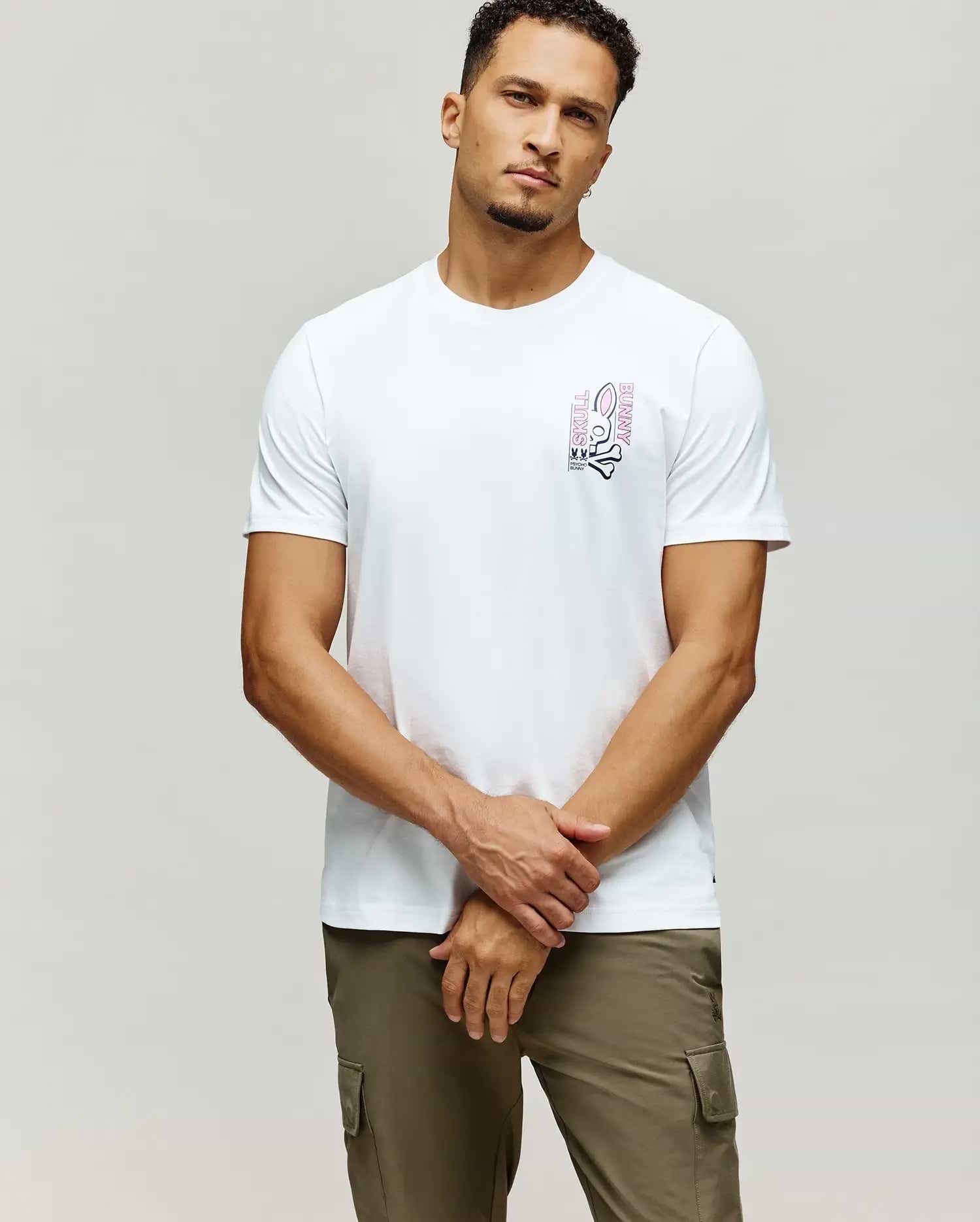 White Mens Skull Bunny Graphic Tee, classic fit, soft jersey fabric, with a vibrant pink and black vertical Skull Bunny graphic on the left chest, featuring the iconic logo and text.