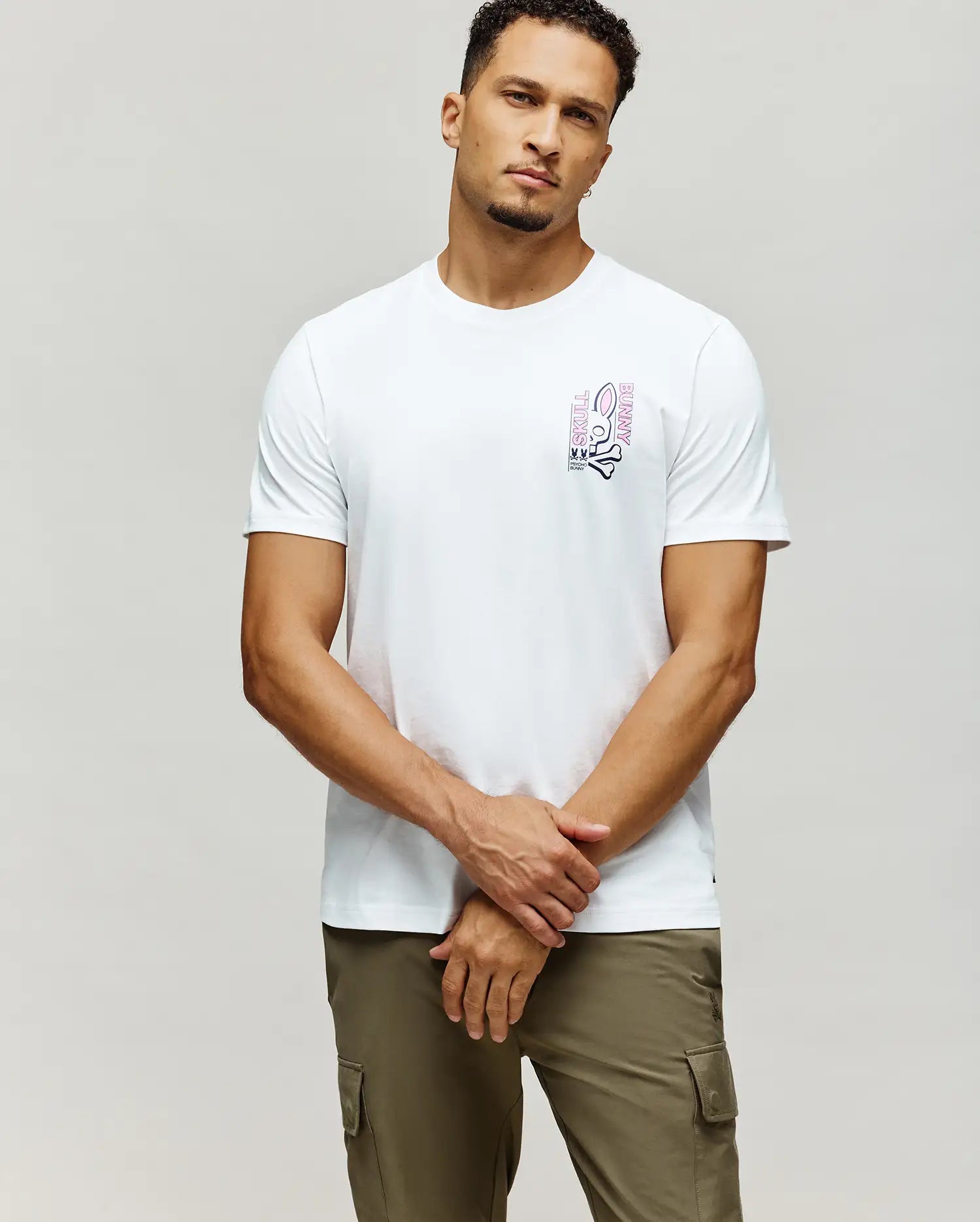 White Mens Skull Bunny Graphic Tee, classic fit, soft jersey fabric, with a vibrant pink and black vertical Skull Bunny graphic on the left chest, featuring the iconic logo and text.