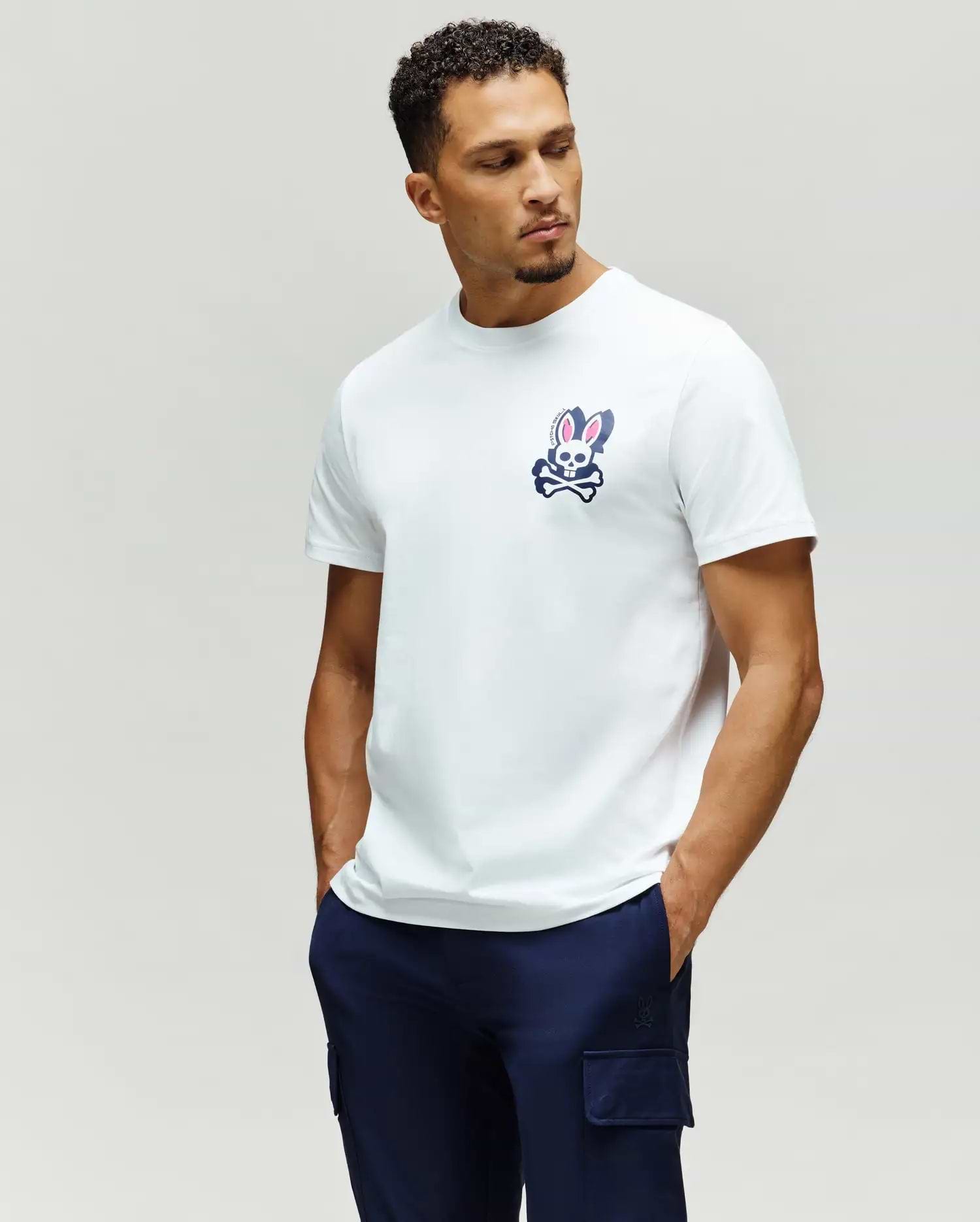 Mens Psycho Skull Graphic Tee. White classic fit jersey t-shirt featuring a prominent navy and pink Psycho Bunny skull and crossbones graphic on the left chest.