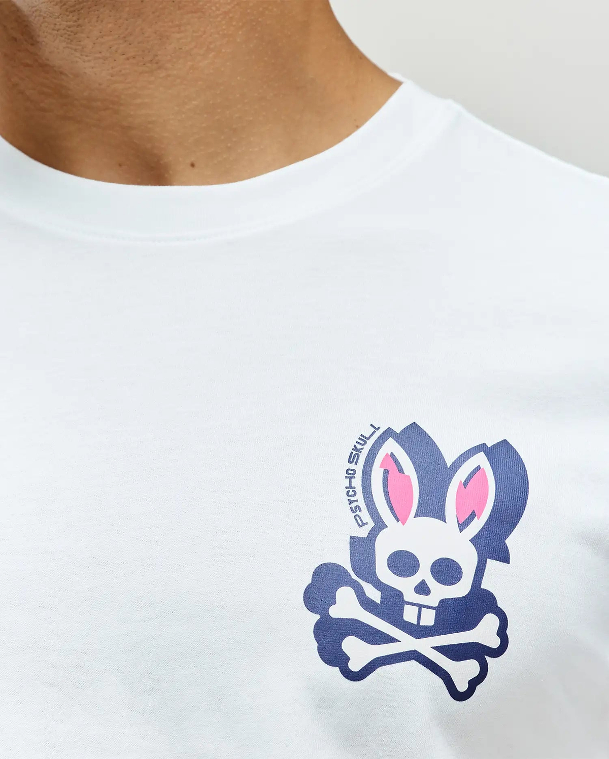Mens Psycho Skull Graphic Tee, a white classic fit jersey t-shirt featuring a navy blue, pink, and white Psycho Bunny skull and crossbones graphic on the left chest with PSYCHO SKULL text.