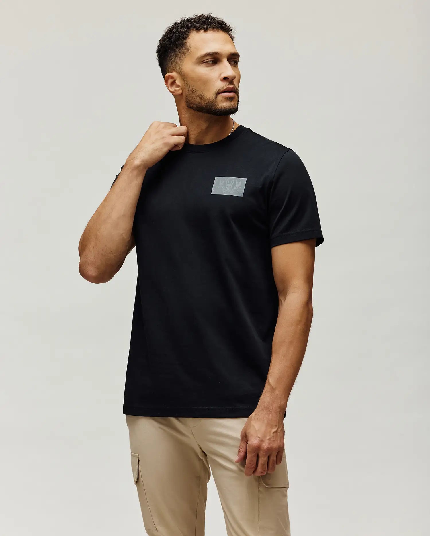 Black Mens Jarvis Chest Graphic Tee, a classic fit jersey t-shirt, featuring a rectangular grey graphic print with multiple iconic Psycho Bunny skull logos on the chest.