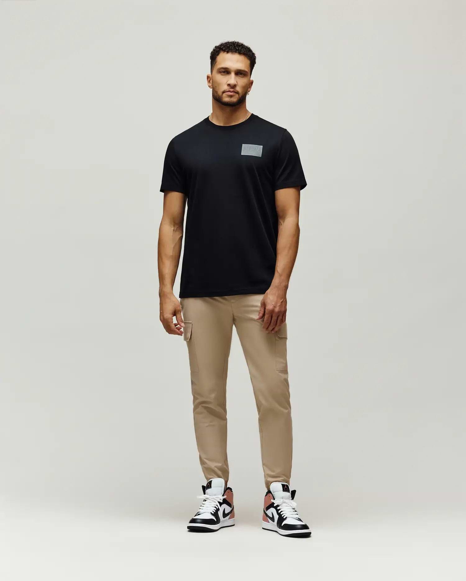 Mens Jarvis Chest Graphic Tee, a classic fit black jersey t-shirt featuring a subtle, reflective silver rectangular Psycho Bunny graphic on the left chest.