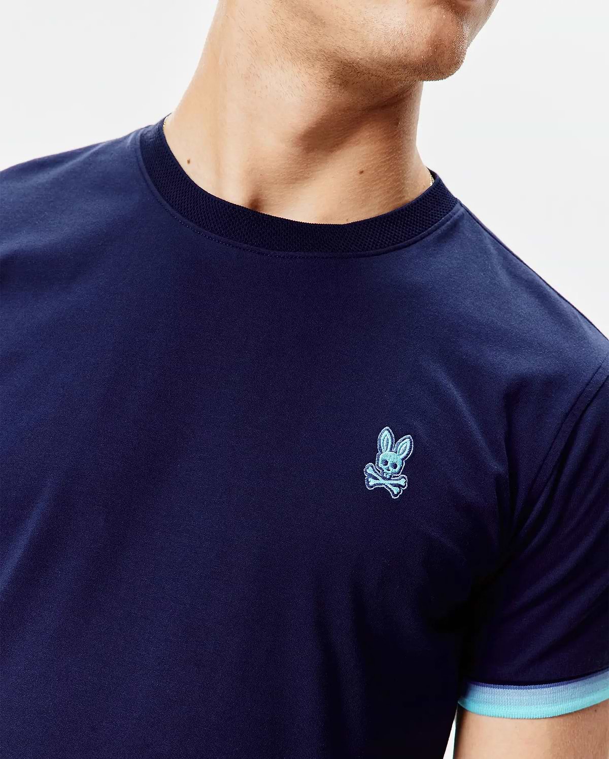 Mens Holden Tee in navy jersey, classic fit, with a small embroidered light blue Psycho Bunny skull logo on the left chest, a ribbed navy crew neck, and striped light blue cuffs. (2)