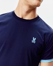 Mens Holden Tee in navy jersey, classic fit, with a small embroidered light blue Psycho Bunny skull logo on the left chest, a ribbed navy crew neck, and striped light blue cuffs. (2)