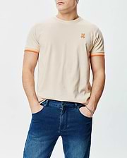 Mens Holden Tee, classic fit, beige jersey with small embroidered orange Psycho Bunny skull logo on left chest and orange striped sleeve cuffs.