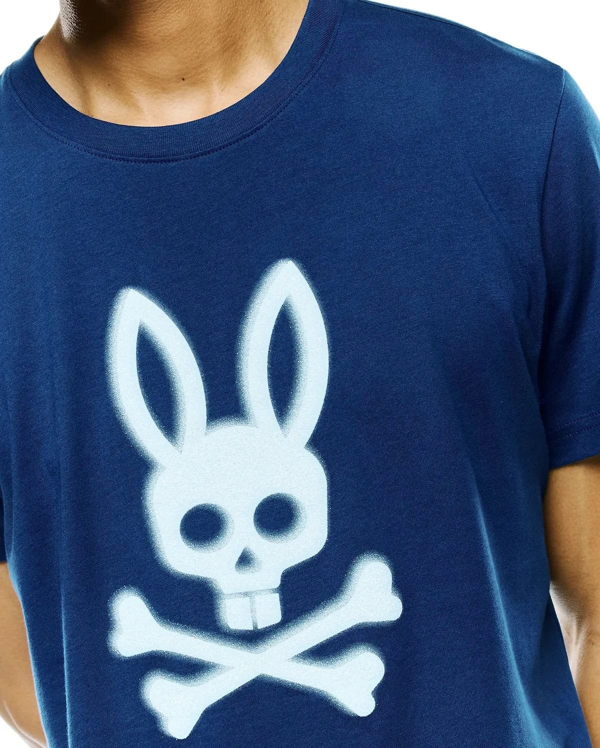 Mens Emmanuel Graphic Tee, a classic fit navy blue jersey t-shirt featuring a large, light blue spray-painted Psycho Bunny skull and crossbones graphic on the center chest.