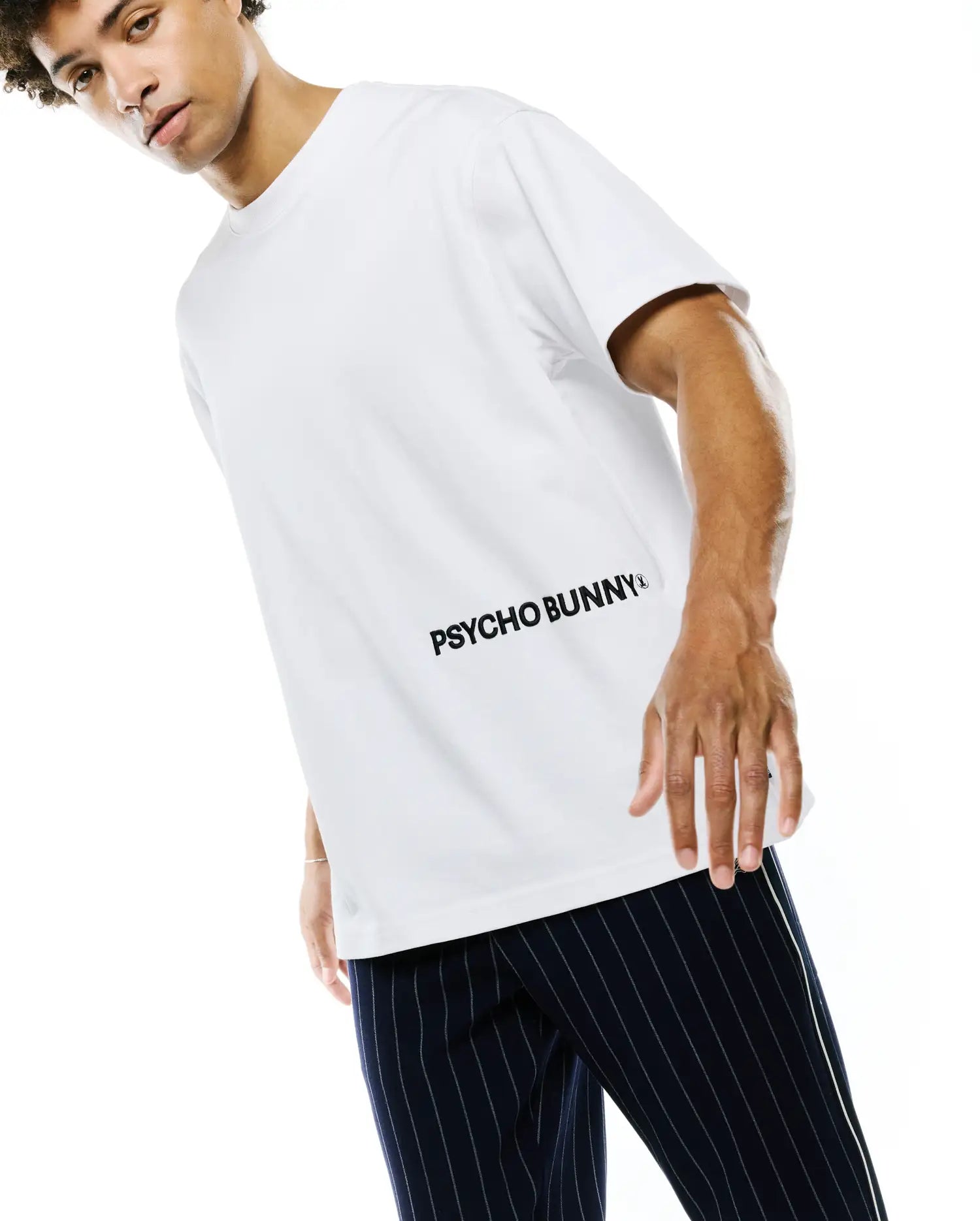 White Mens Haiden Relaxed Heavy Weight Tee featuring a large, diagonal black PSYCHO BUNNY text logo with a small bunny skull icon on the lower chest, made from smooth heavyweight jersey fabric.
