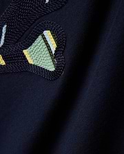Mens Drew Embroidered Graphic Tee, a dark navy jersey knit with a prominent, textured Psycho Bunny skull logo detail featuring light blue, yellow, and green stripes.