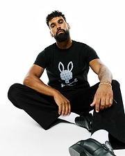 Mens Jaden Appliqué Graphic Tee: Black classic fit jersey t-shirt featuring a large central grey and white Psycho Bunny skull logo with a repeating mini-logo pattern.