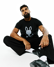 Mens Jaden Appliqué Graphic Tee: Black classic fit jersey t-shirt featuring a large central grey and white Psycho Bunny skull logo with a repeating mini-logo pattern.