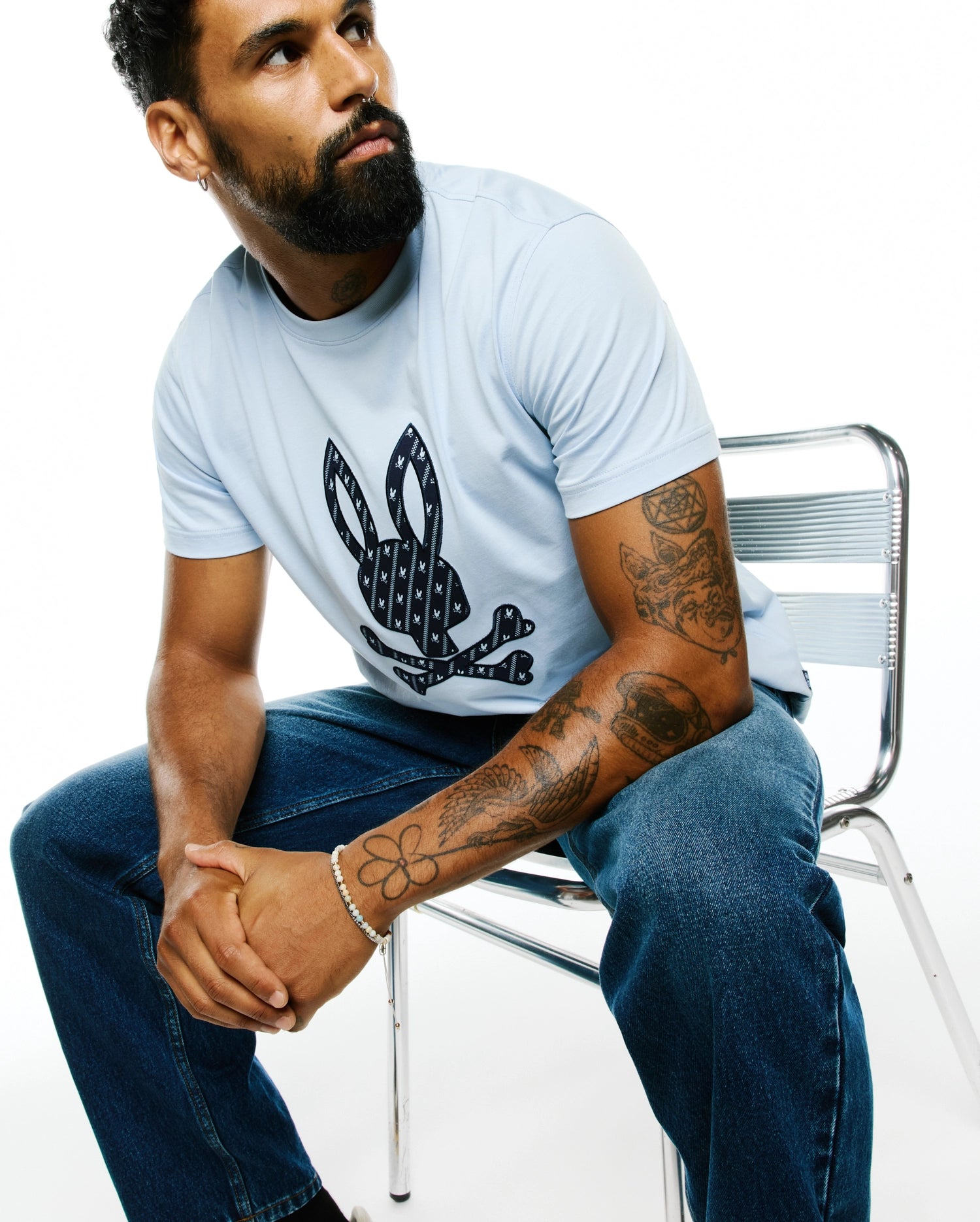 Sky blue Mens Jaden Appliqué Graphic Tee, classic fit, with a large textured navy Psycho Bunny skull logo on the chest, filled with mini bunny patterns.