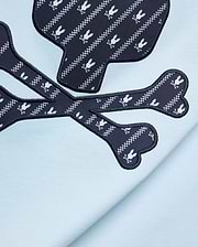 Mens Jaden Graphic Tee in light blue jersey knit, featuring a large navy blue skull and crossbones graphic with white Psycho Bunny logo and checkered stripe pattern, outlined in black embroidery.