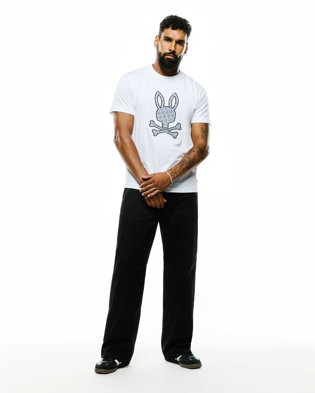 Mens Jaden Appliqué Graphic Tee, a white classic fit soft jersey t-shirt featuring a large center chest Psycho Bunny skull logo with a repeating bunny pattern and crossed bones.
