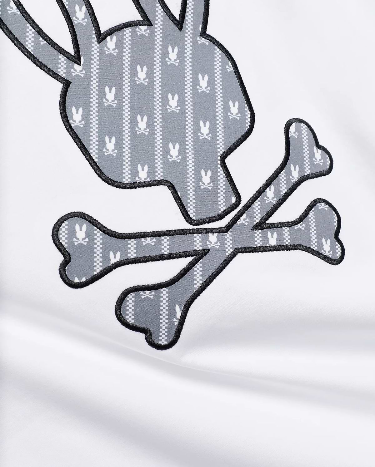 MENS JADEN APPLIQUÉ GRAPHIC TEE featuring a large white jersey fabric with a grey and white patterned bunny skull and crossbones appliqué, outlined in black embroidery.