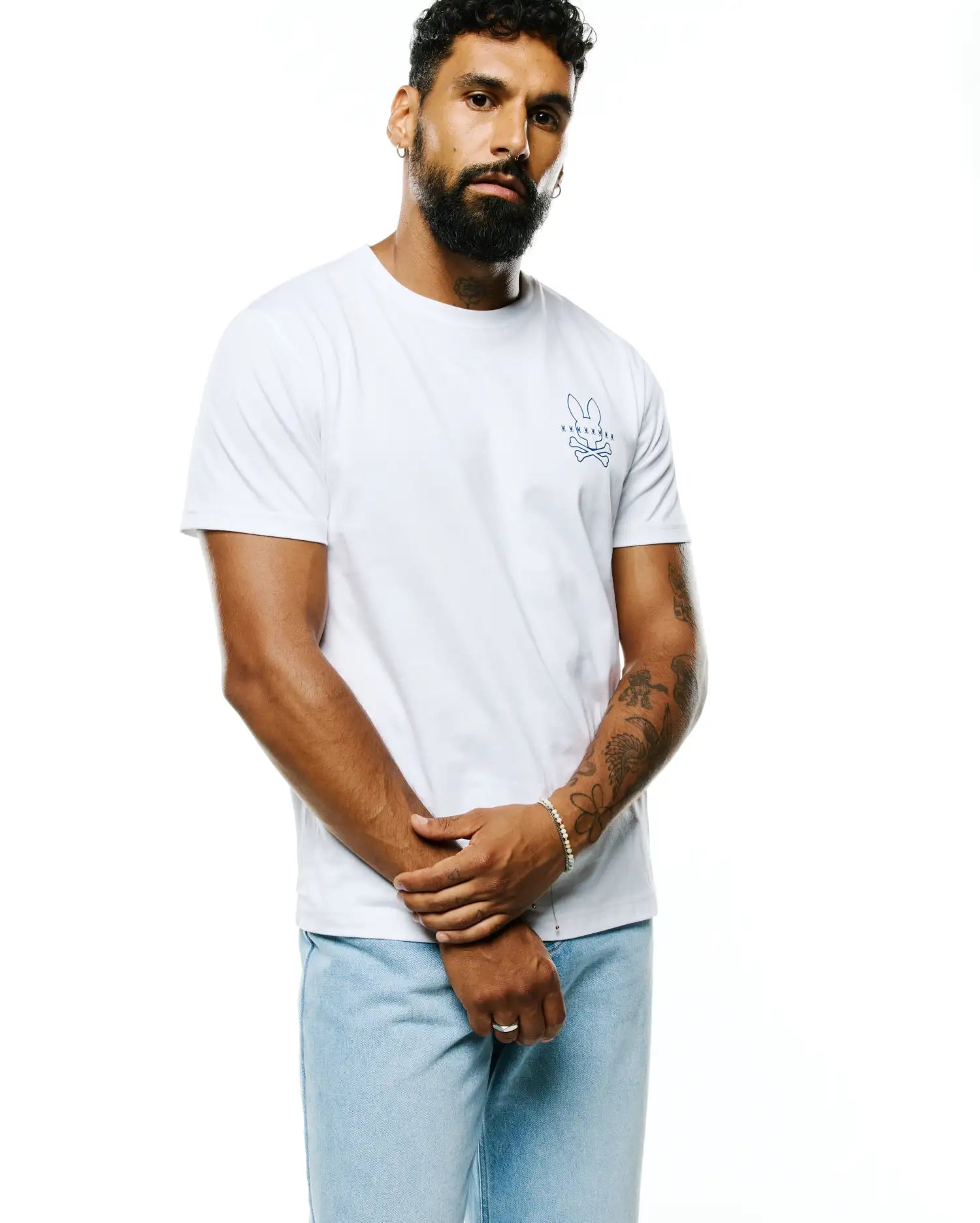 Mens Piers Pima Cotton Back Graphic Tee, a classic fit white jersey t-shirt featuring a small, embroidered blue Psycho Bunny skull logo on the left chest.