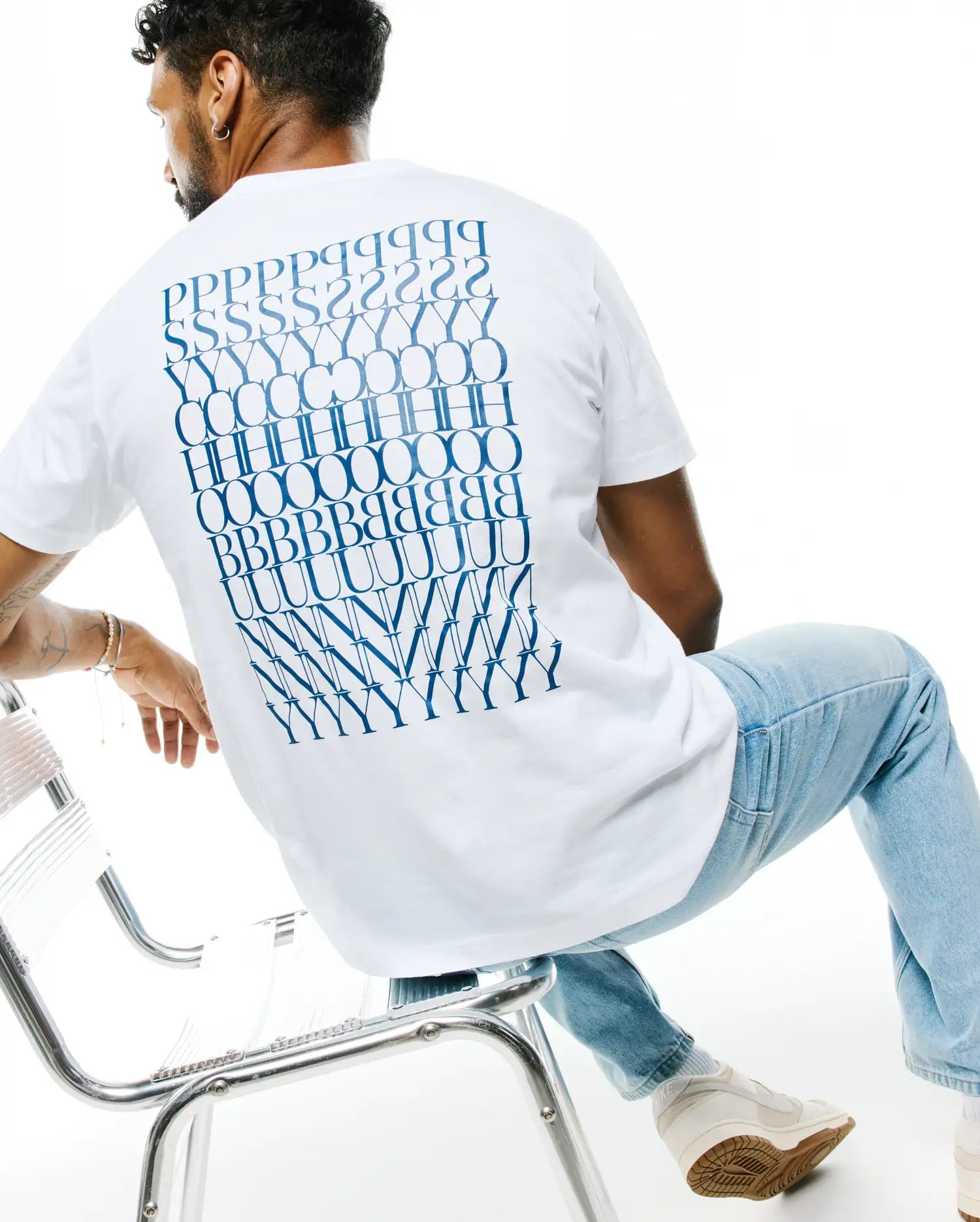 Mens Piers Pima Cotton Back Graphic Tee, a classic fit white jersey t-shirt featuring a large, bold blue stacked PSYCHO BUNNY text graphic covering the entire back.