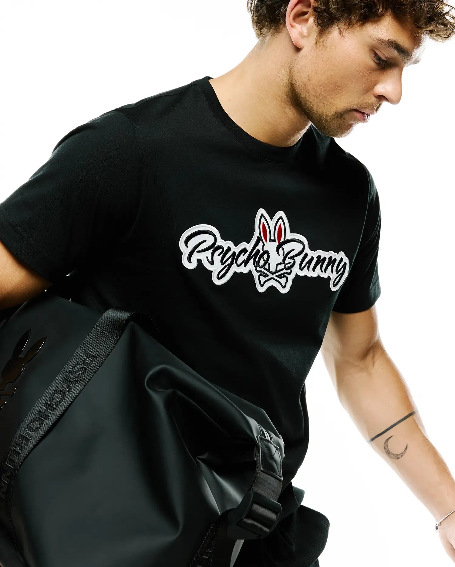 Black Mens Jaydon Wordmark Graphic Tee, classic fit, featuring a large white and red Psycho Bunny wordmark and skull logo graphic on the chest, crafted from soft jersey fabric.
