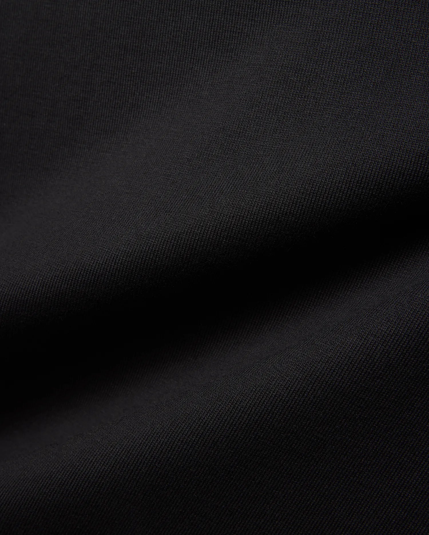 Mens Jaydon Relaxed Fit Tee in deep black, crafted from a premium, soft-touch jersey knit fabric with a subtle, refined texture, embodying Psycho Bunny's signature comfortable streetwear aesthetic.