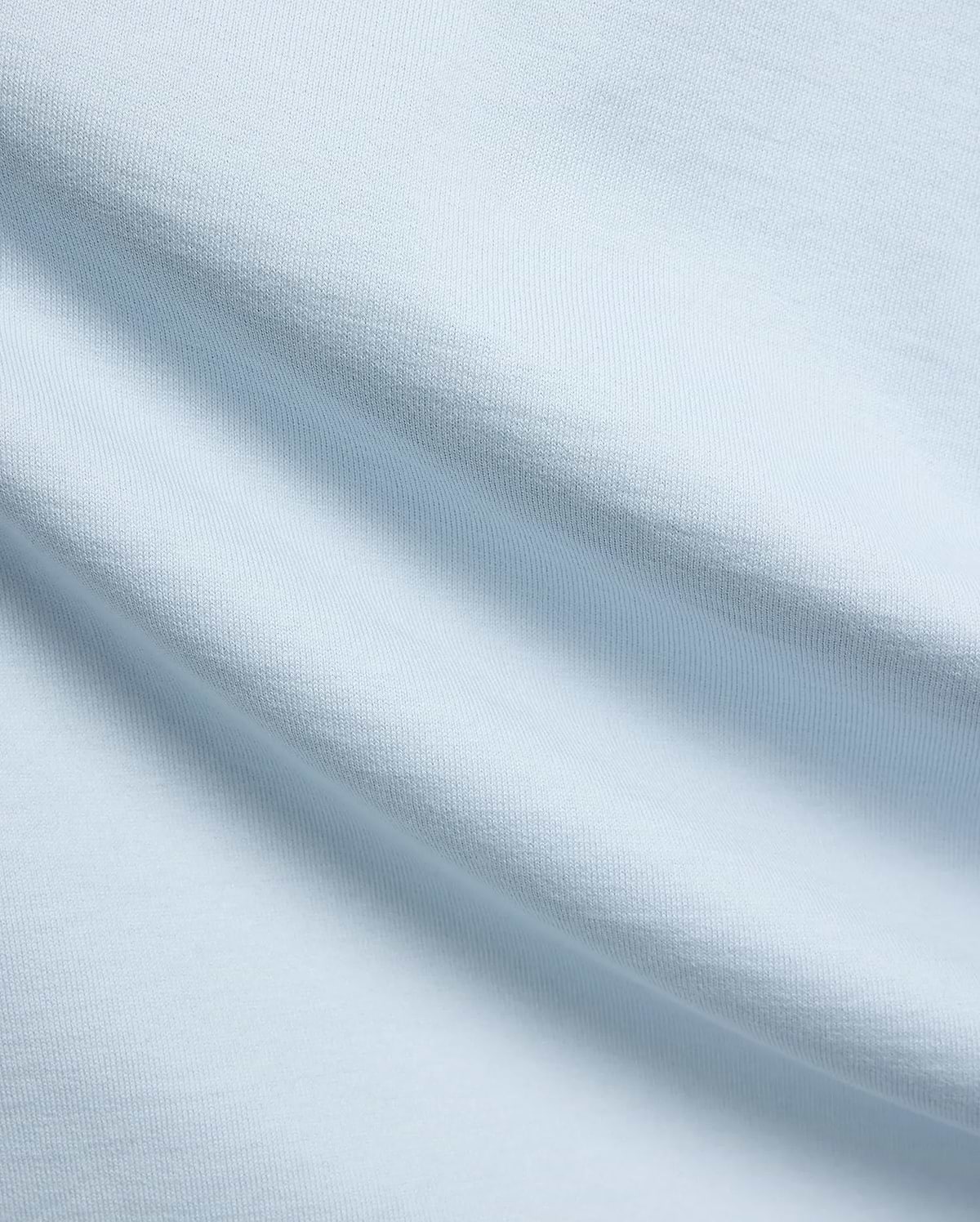 Mens Jaydon Relaxed Fit Tee, a premium light blue jersey knit fabric with a soft, smooth feel and subtle horizontal texture, reflecting Psycho Bunny's refined streetwear quality.