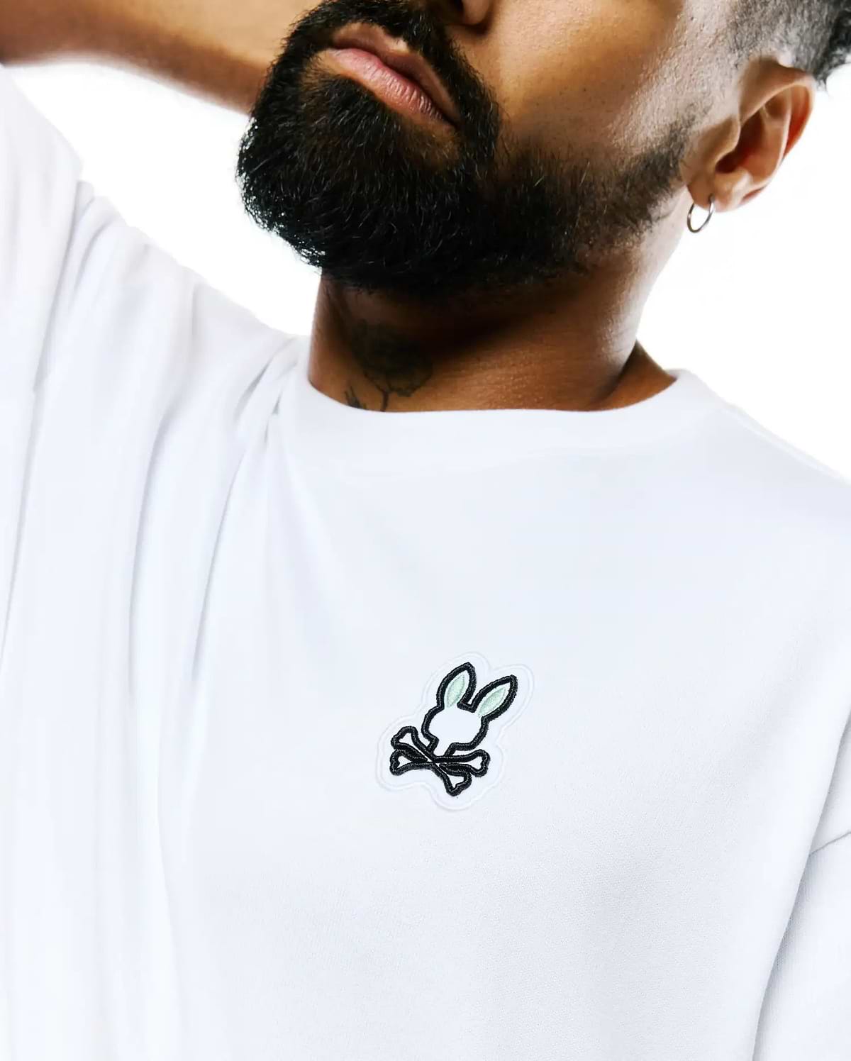 Mens Jaydon Pima Cotton Oversized-Fit Tee in crisp white, featuring a smooth jersey texture and a prominent embroidered Psycho Bunny skull logo with black outline and light green ears on the left chest.