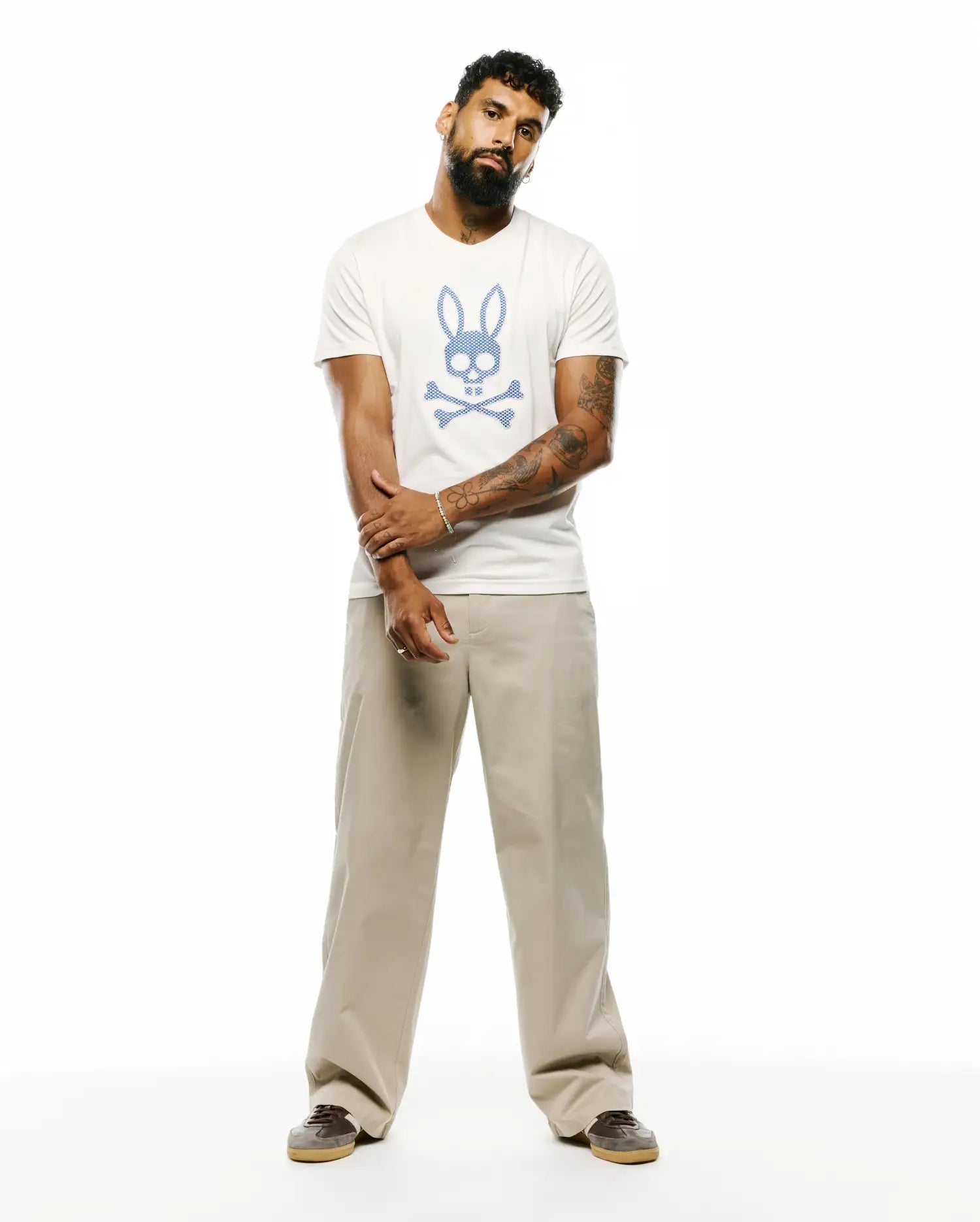 Mens Stan Pima Cotton Graphic Tee, an off-white classic fit t-shirt featuring a large, central textured blue Psycho Bunny skull and crossbones graphic on smooth Pima cotton jersey.