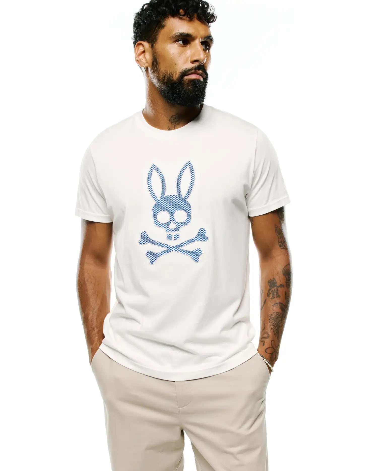 Mens Stan Pima Cotton Graphic Tee, a classic fit cream jersey t-shirt featuring a large blue checkered Psycho Bunny skull and crossbones graphic on the chest.