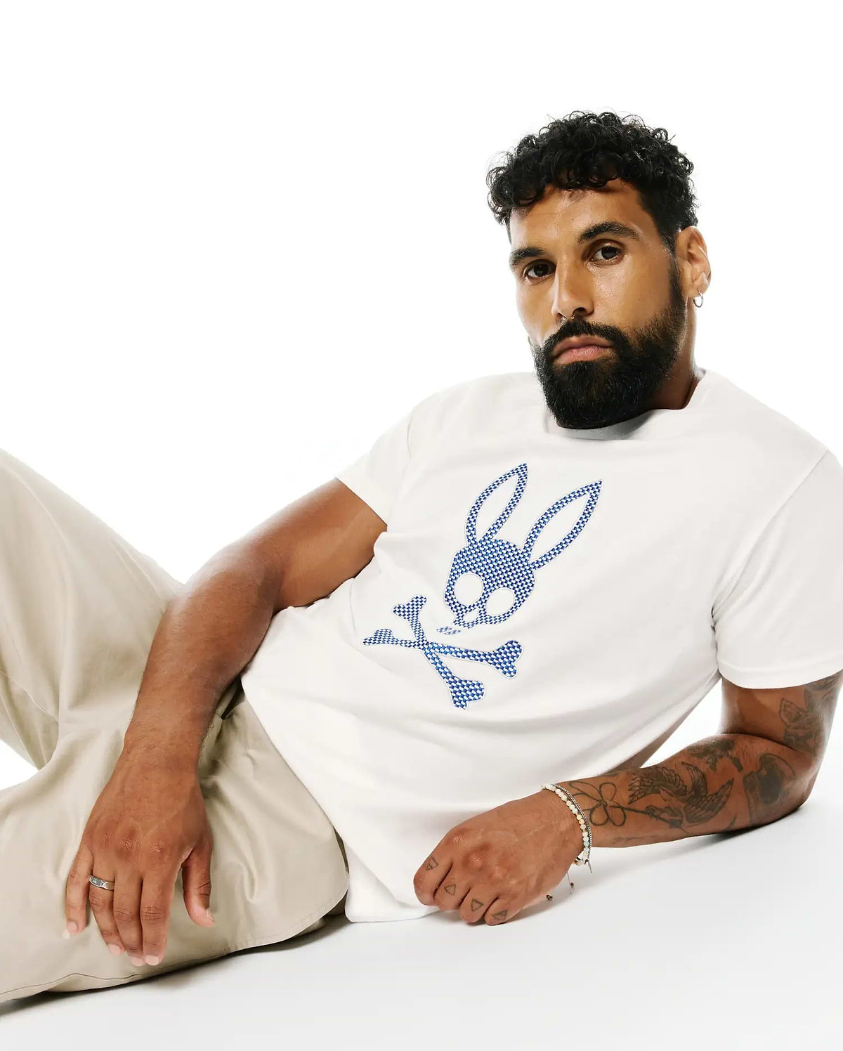 Mens Stan Pima Cotton Graphic Tee, a classic fit white premium Pima cotton jersey t-shirt featuring a large, central blue checkered Psycho Bunny skull logo.