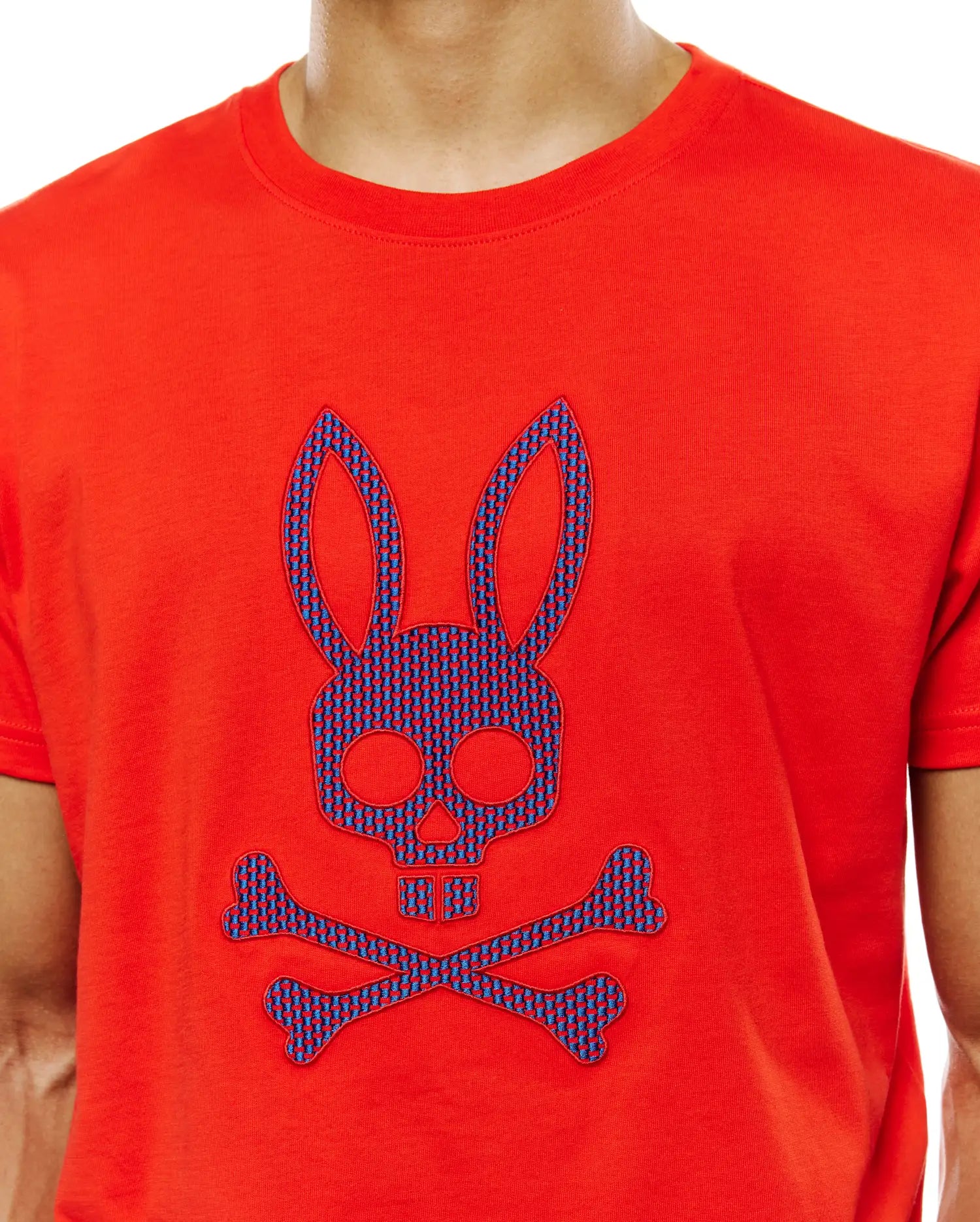 Mens Stan Graphic Tee, a classic fit red jersey knit t-shirt featuring a large central chest Psycho Bunny skull and crossbones logo with a blue and red patterned fill.