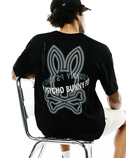Mens Alex Relaxed Back Graphic Tee in black jersey knit, featuring a large white and grey dotted Psycho Bunny skull graphic on the back and vertical Psycho Bunny text along the shoulders.