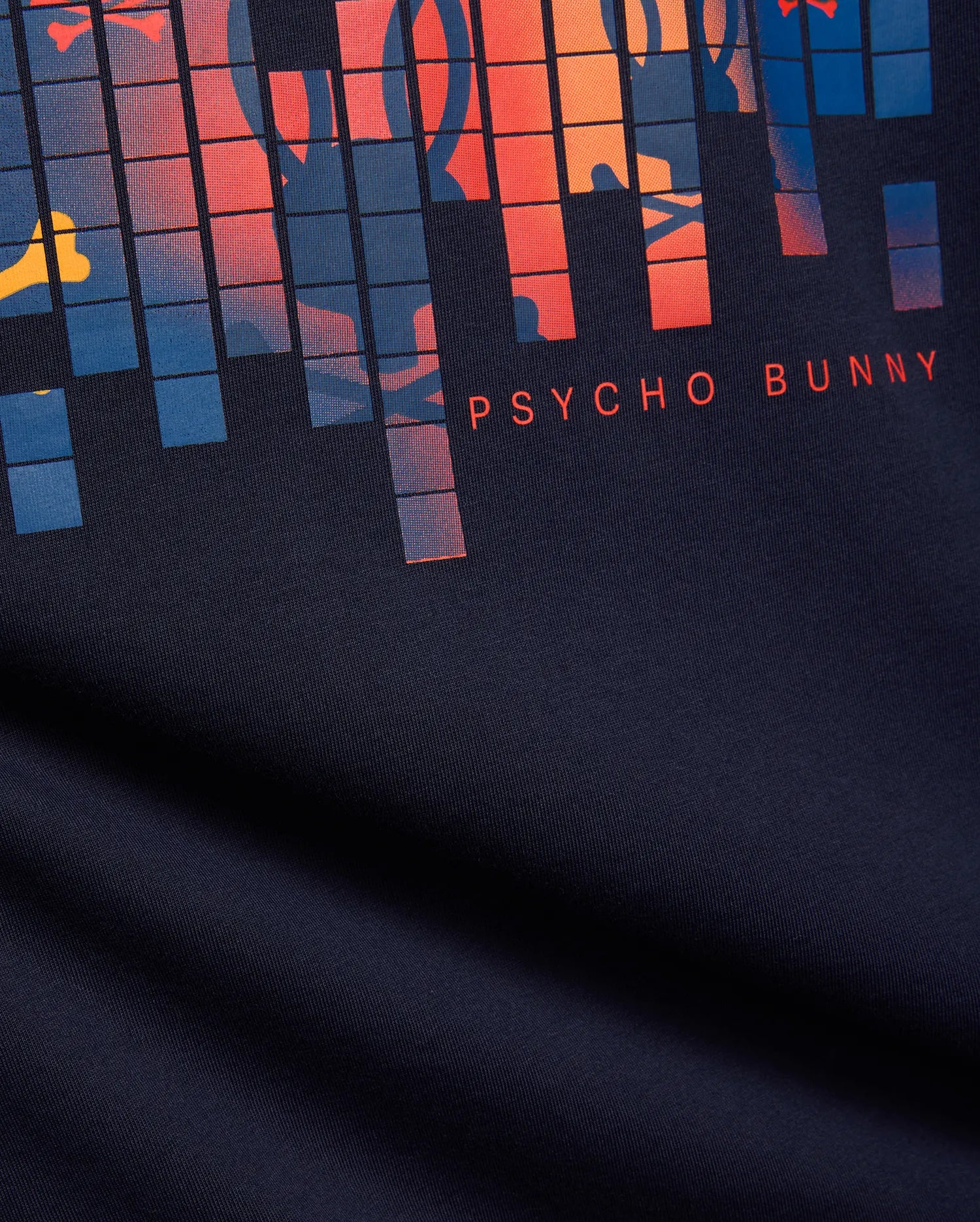 Mens Zander Graphic Tee, a classic fit navy jersey t-shirt with a bold, pixelated chest graphic in vibrant orange, red, blue, and yellow, subtly incorporating the bunny skull, and a small red PSYCHO BUNNY text logo.