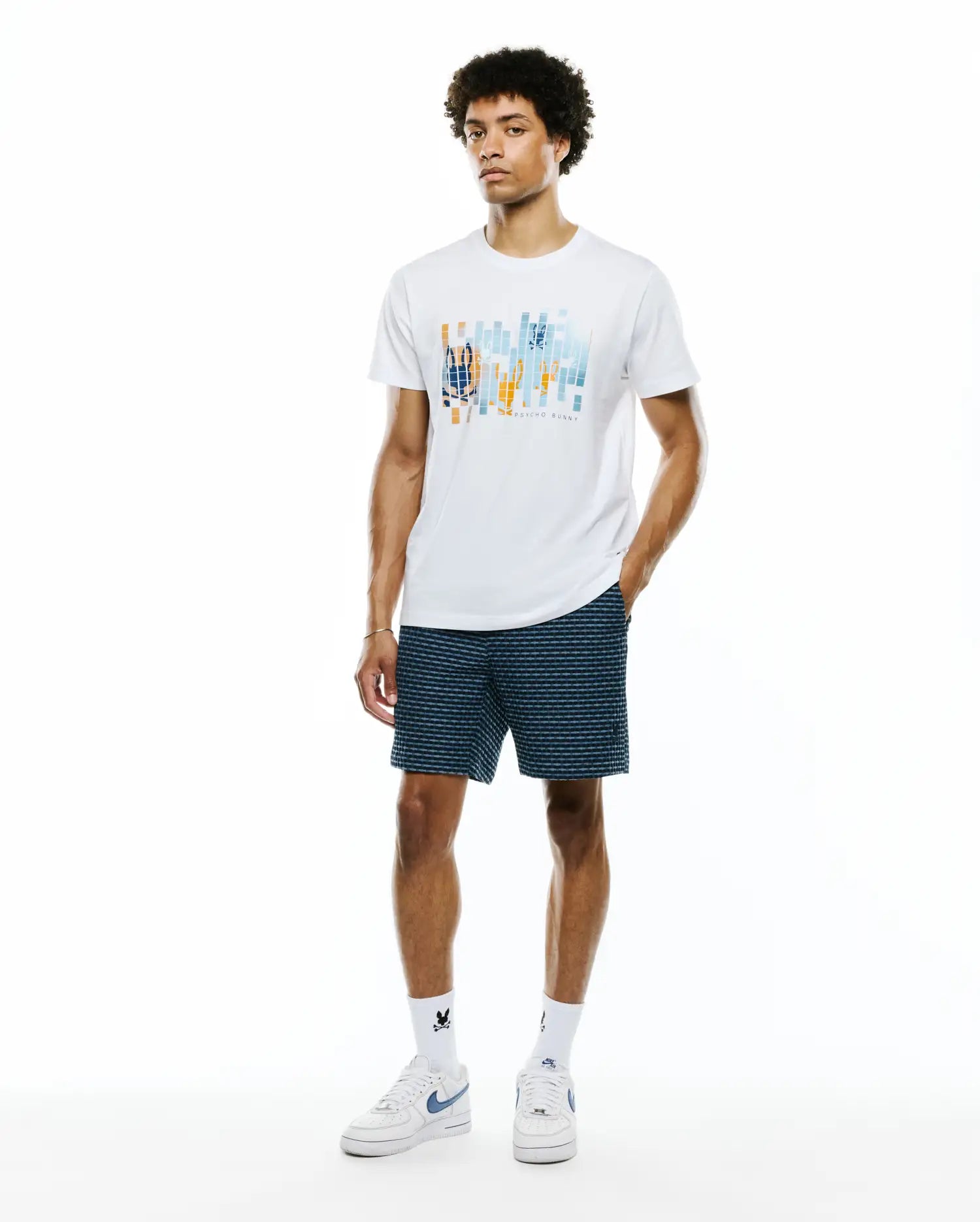 White Mens Zander Graphic Tee, classic fit jersey, with a vibrant abstract orange and blue geometric chest graphic subtly featuring the iconic bunny skull and PSYCHO BUNNY text.