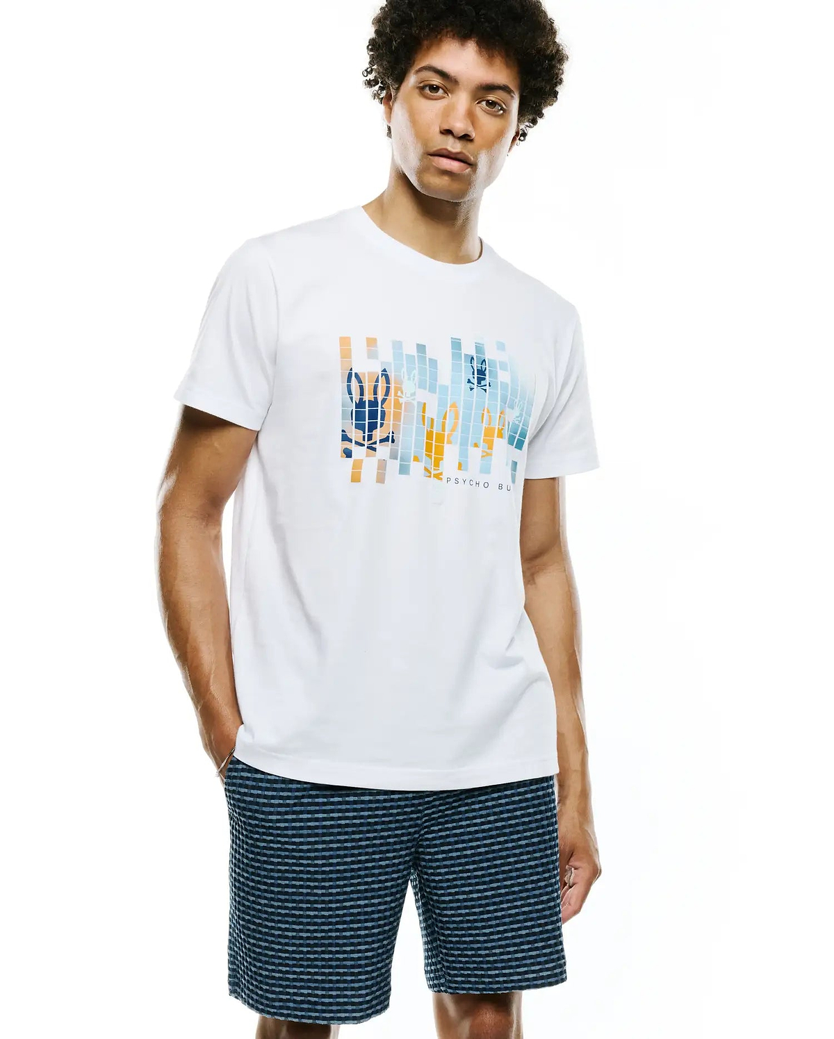 White classic fit jersey Mens Zander Graphic Tee featuring a large central pixelated graphic of the Psycho Bunny skull logo and text in orange, blue, and light blue blocks.
