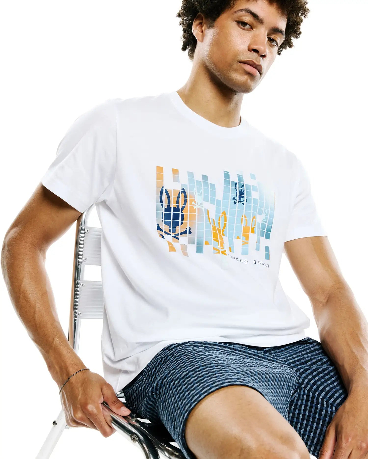 Mens Zander Graphic Tee, a white classic fit jersey t-shirt with a prominent pixelated blue and orange Psycho Bunny skull graphic on the chest, featuring subtle brand text below.