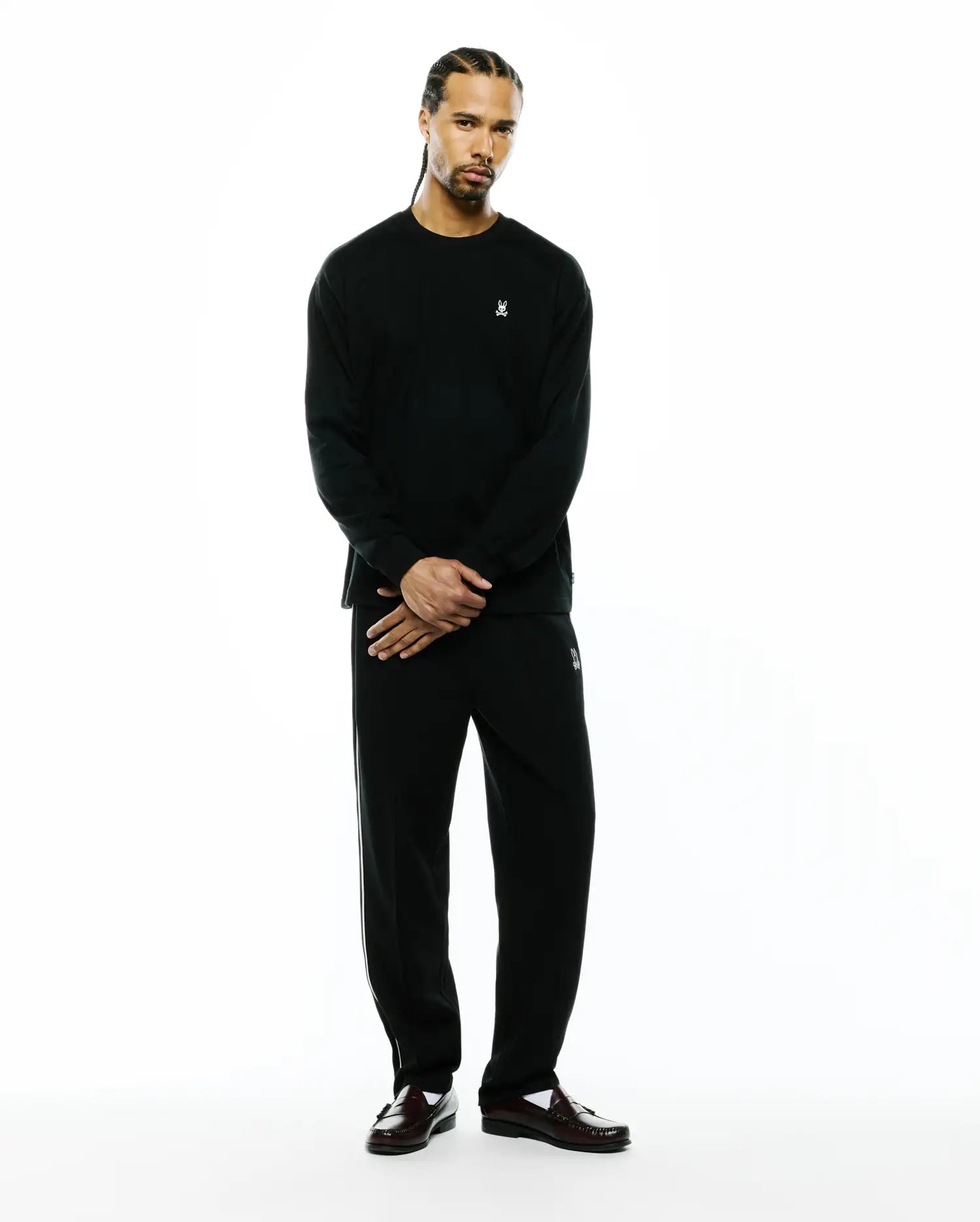 Black Mens Norman Long Sleeve Oversized Fit Tee with small white embroidered bunny skull on chest, and black relaxed track pants with white side stripes and an embroidered bunny skull on left thigh.