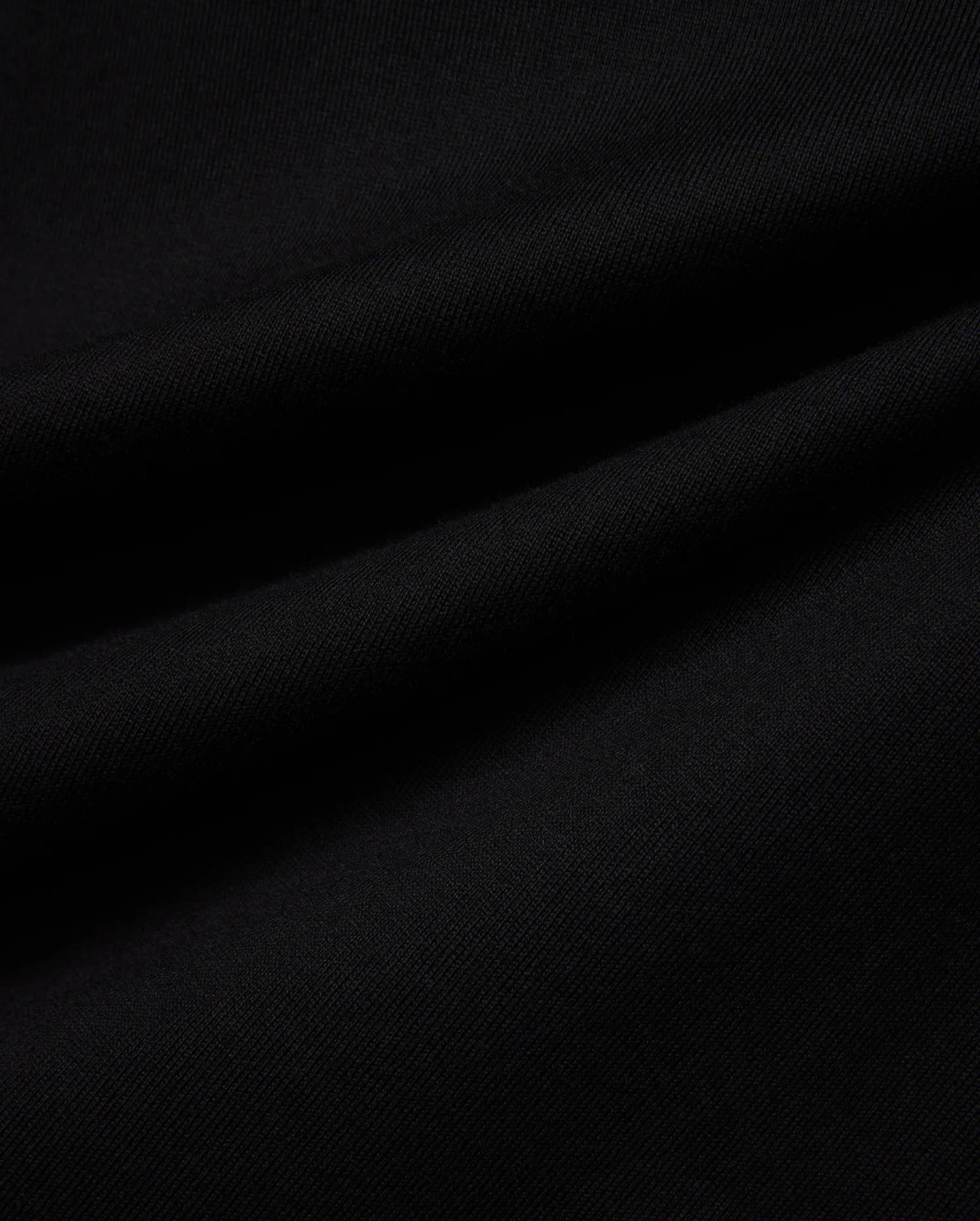 Mens Norman Long Sleeve Oversized Fit Tee in rich, solid black, showcasing a premium, soft-touch jersey knit fabric with a subtle, fine diagonal texture and natural draping folds.
