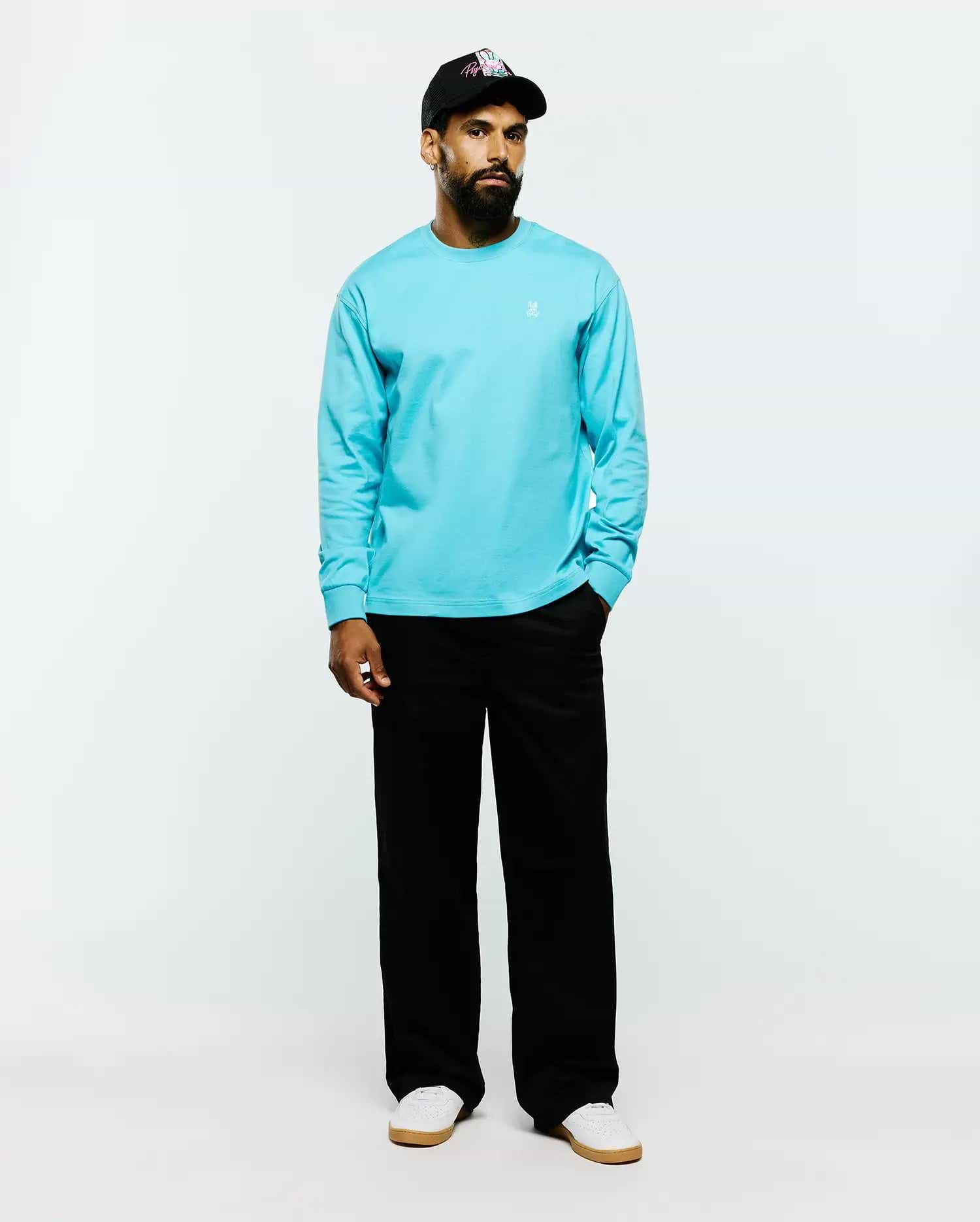 Mens Norman Long Sleeve Relaxed Fit Tee in vibrant aqua blue, crafted from smooth jersey fabric with a relaxed fit and a small white embroidered Psycho Bunny skull logo on the left chest.