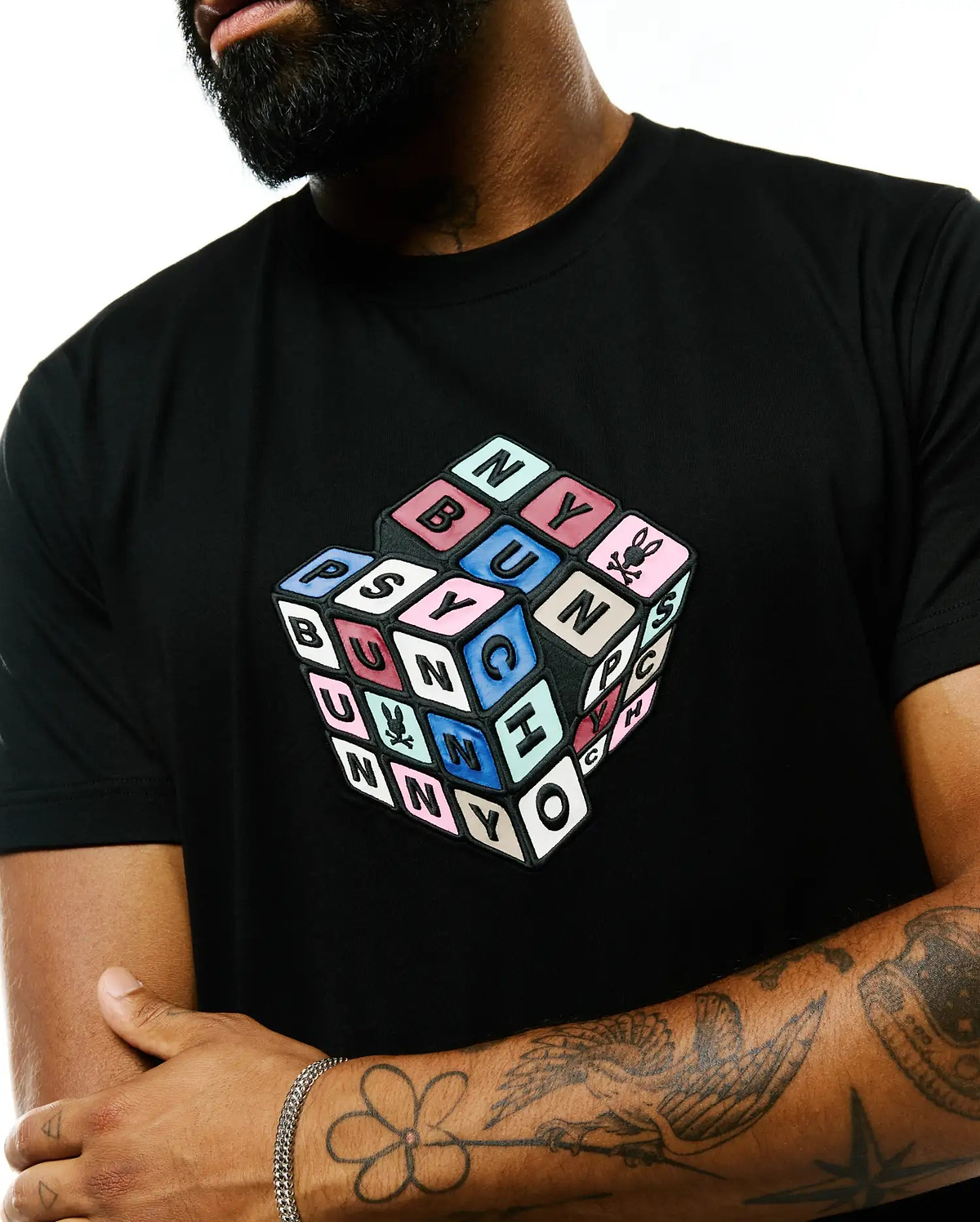 Black Mens Eddy Graphic Tee, classic fit, smooth jersey, with a large, textured 3D cube graphic on the chest spelling PSYCHO BUNNY in multi-colored blocks, featuring the iconic bunny skull logo.