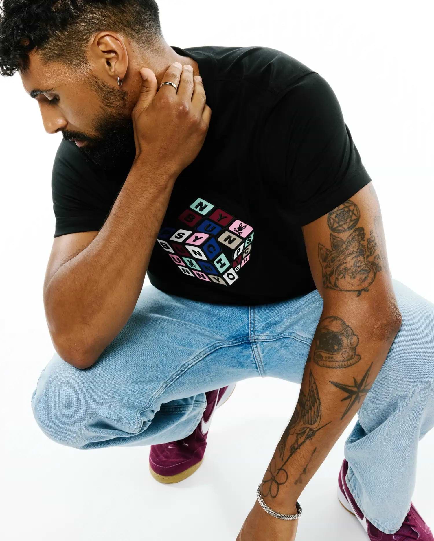 Mens Eddy Graphic Tee: Black classic fit jersey knit t-shirt featuring a large central multicolor Rubik's Cube-style graphic with individual colored squares spelling PSYCHO BUNNY.