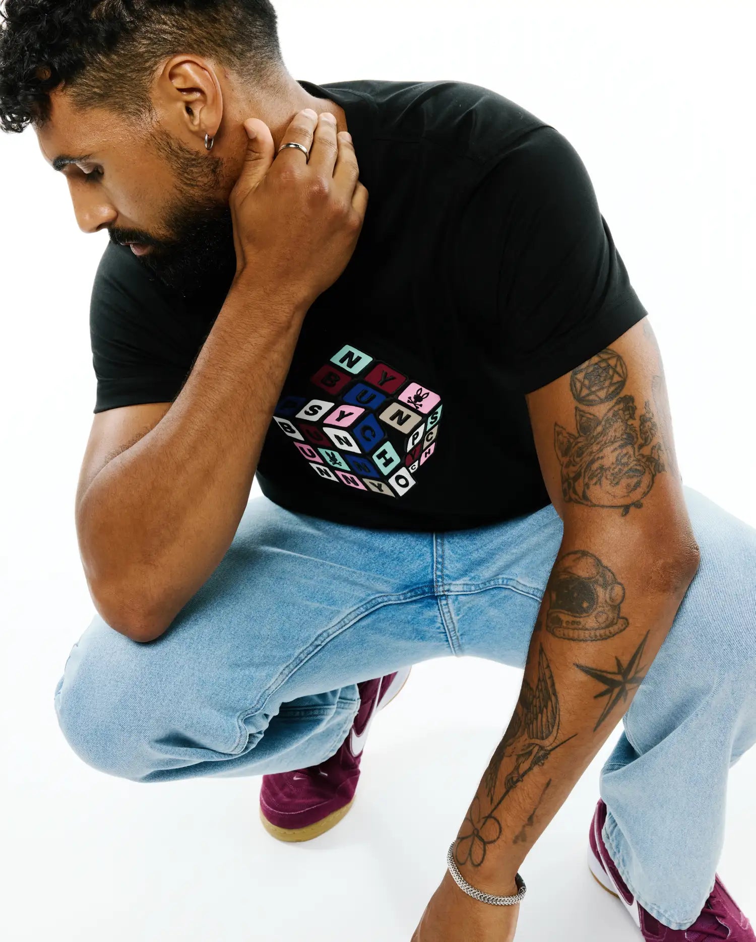 Mens Eddy Graphic Tee: Black classic fit jersey knit t-shirt featuring a large central multicolor Rubik's Cube-style graphic with individual colored squares spelling PSYCHO BUNNY.