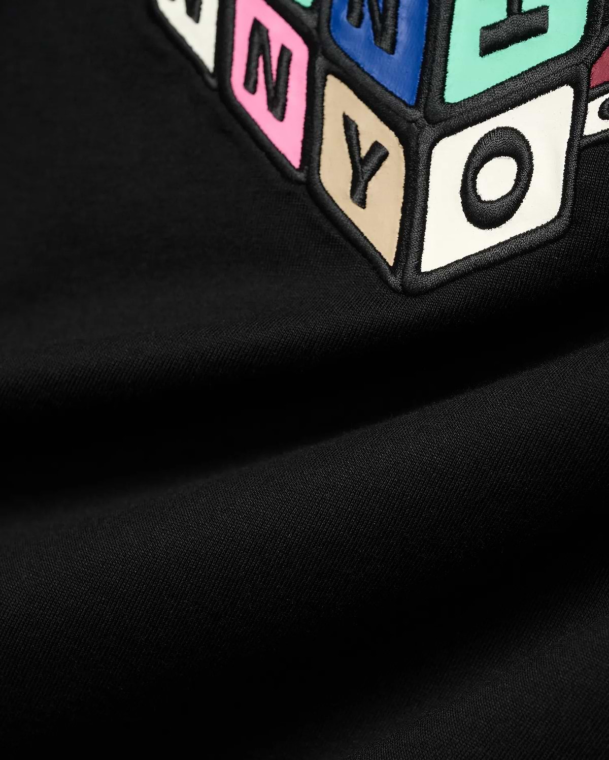 Mens Eddy Graphic Tee, black jersey t-shirt featuring a large, central, raised graphic of colorful block letters with black outlines, including pink N, blue Y, beige Y, and white O.