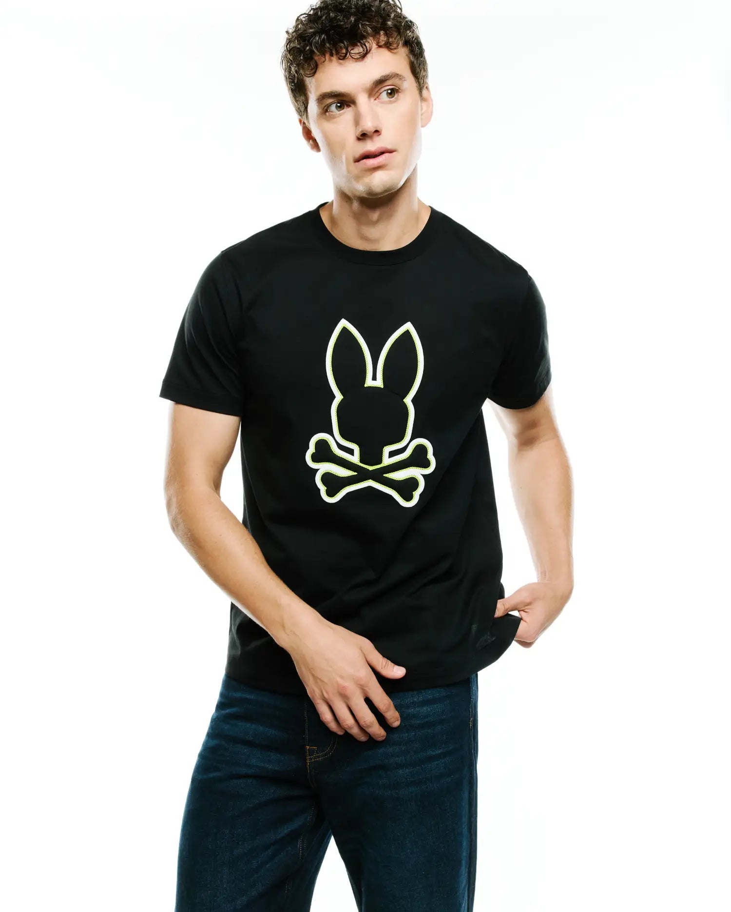 Mens Bruno Graphic Tee, a black classic fit jersey knit t-shirt featuring a large, centered Psycho Bunny skull and crossbones logo with a prominent white and neon yellow outline.