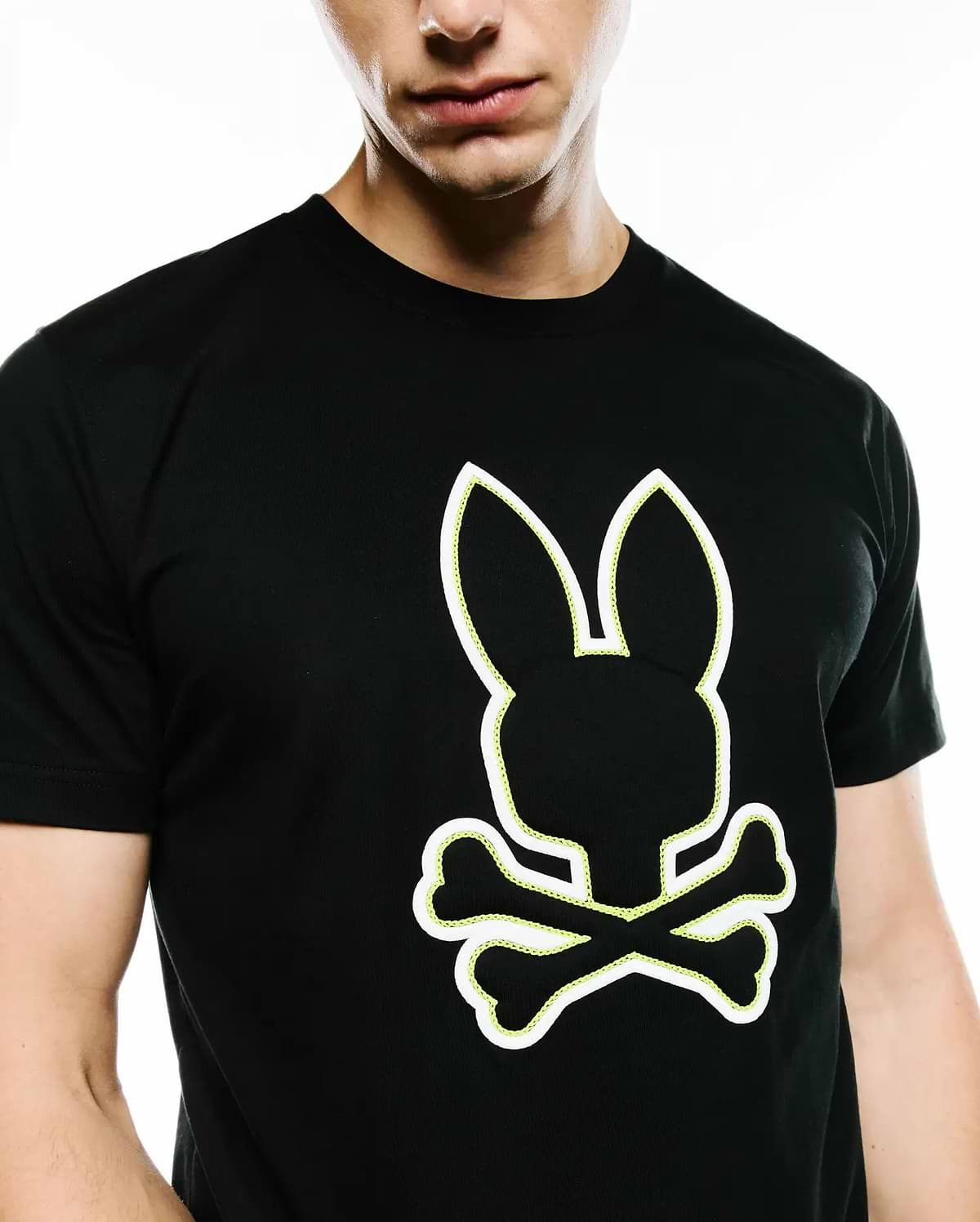 Mens Bruno Graphic Tee, a black classic fit jersey t-shirt featuring a prominent white outline Psycho Bunny skull logo with vibrant neon yellow stitching detail on the chest.