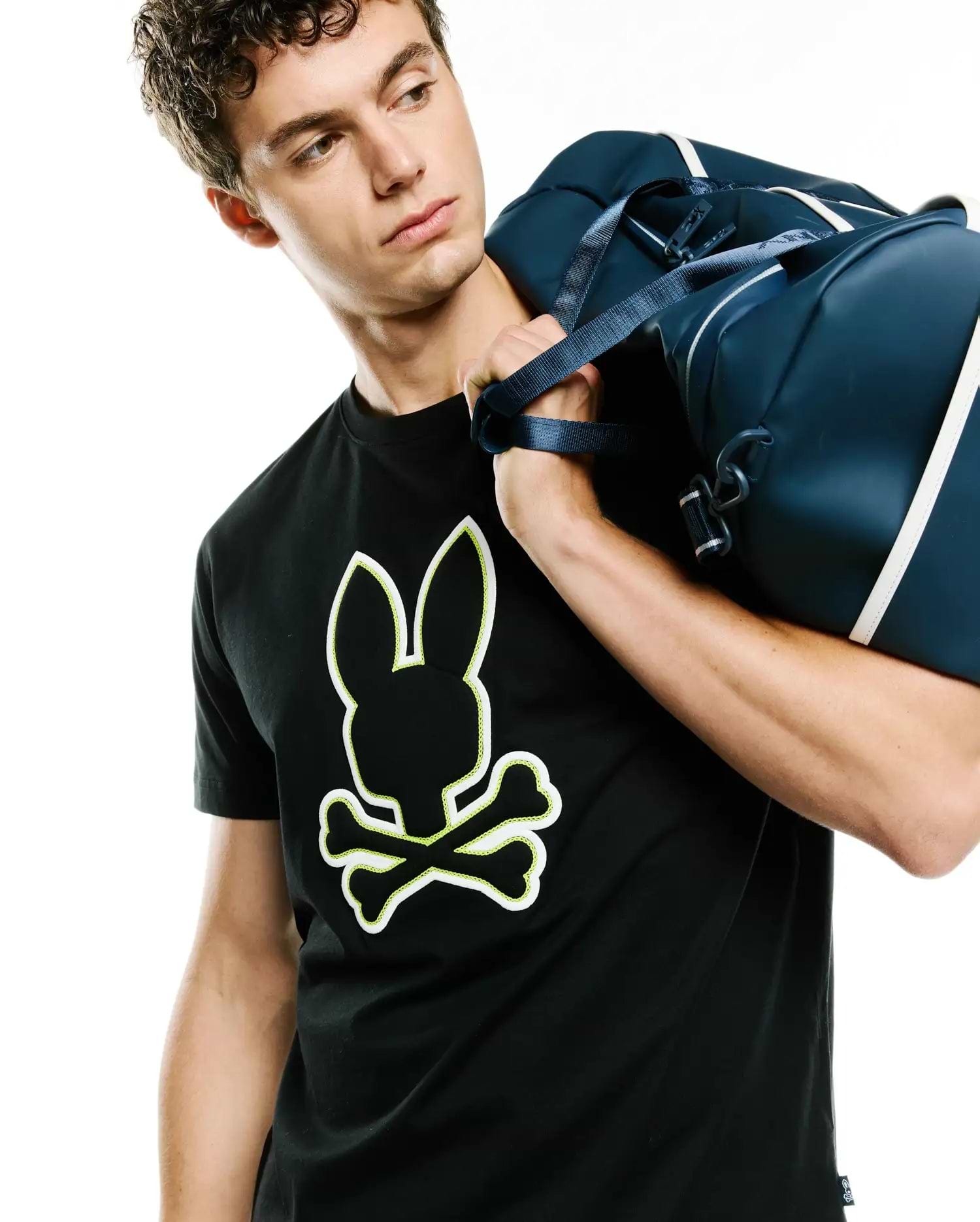 Mens Bruno Graphic Tee, black classic fit jersey knit t-shirt featuring a large central Psycho Bunny skull logo with white fill and neon yellow outline.