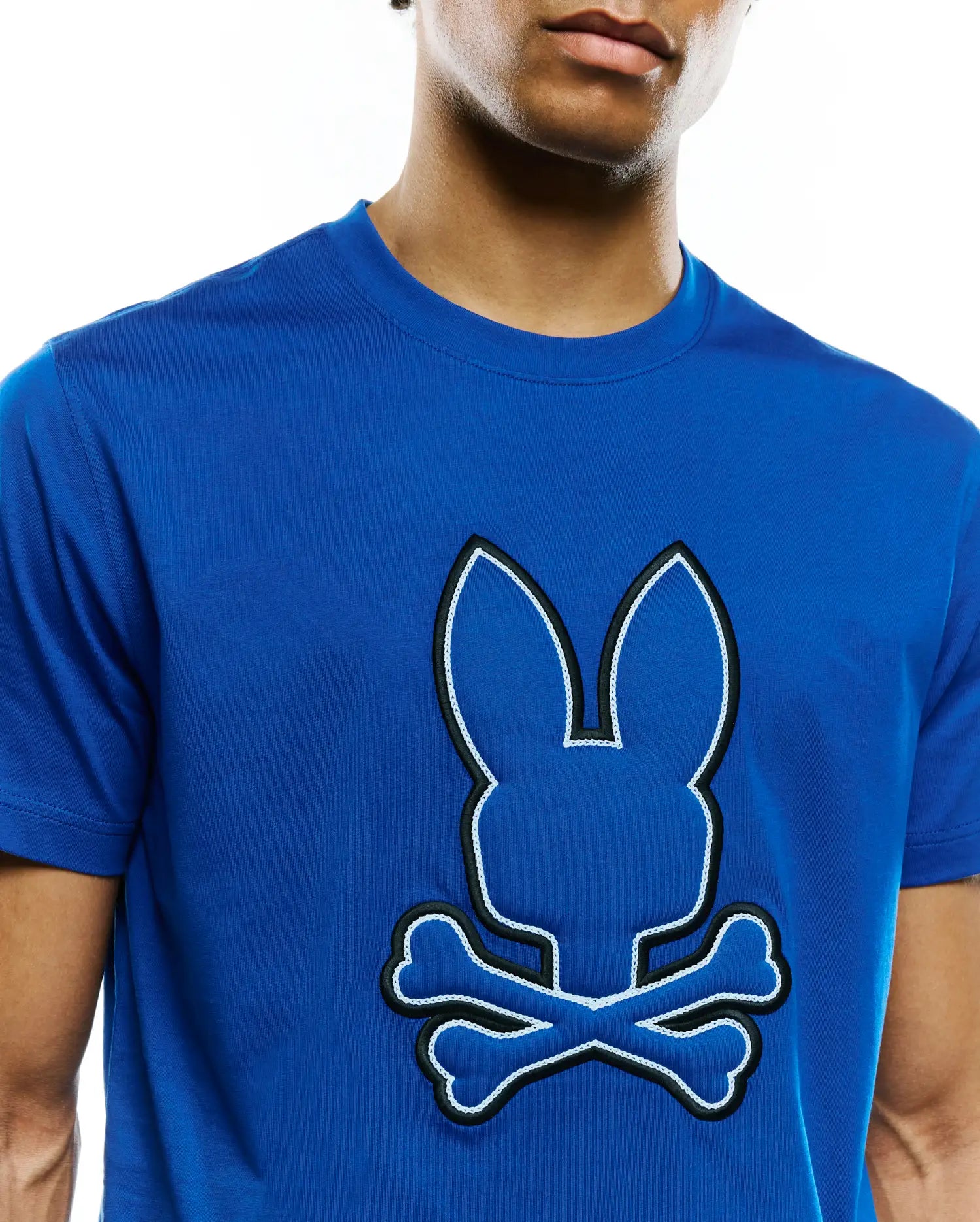 Mens Bruno Graphic Tee, a vibrant royal blue jersey t-shirt with a large, central tone-on-tone Psycho Bunny skull logo outlined in black embroidery and white stitching, featuring a classic fit.