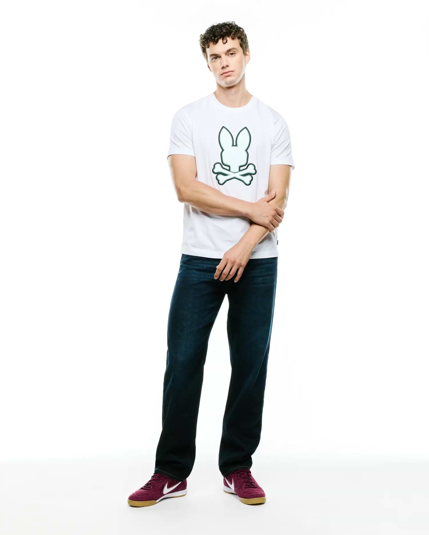 Mens Bruno Graphic Tee, a classic fit white jersey t-shirt featuring a prominent, centered green outline Psycho Bunny skull and crossbones logo graphic on the chest.
