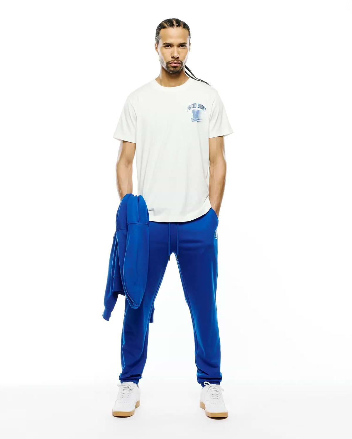 Mens Nathaniel Back Graphic Tee, an off-white jersey t-shirt with a blue Psycho Bunny chest graphic, paired with royal blue French terry joggers and a matching hoodie.