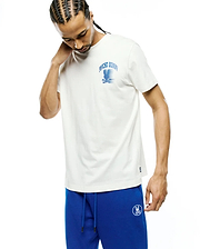Mens Nathaniel Back Graphic Tee, a cream jersey t-shirt with a classic fit, featuring a prominent blue distressed Psycho Bunny skull graphic print on the chest and a subtle woven logo tag on the hem.